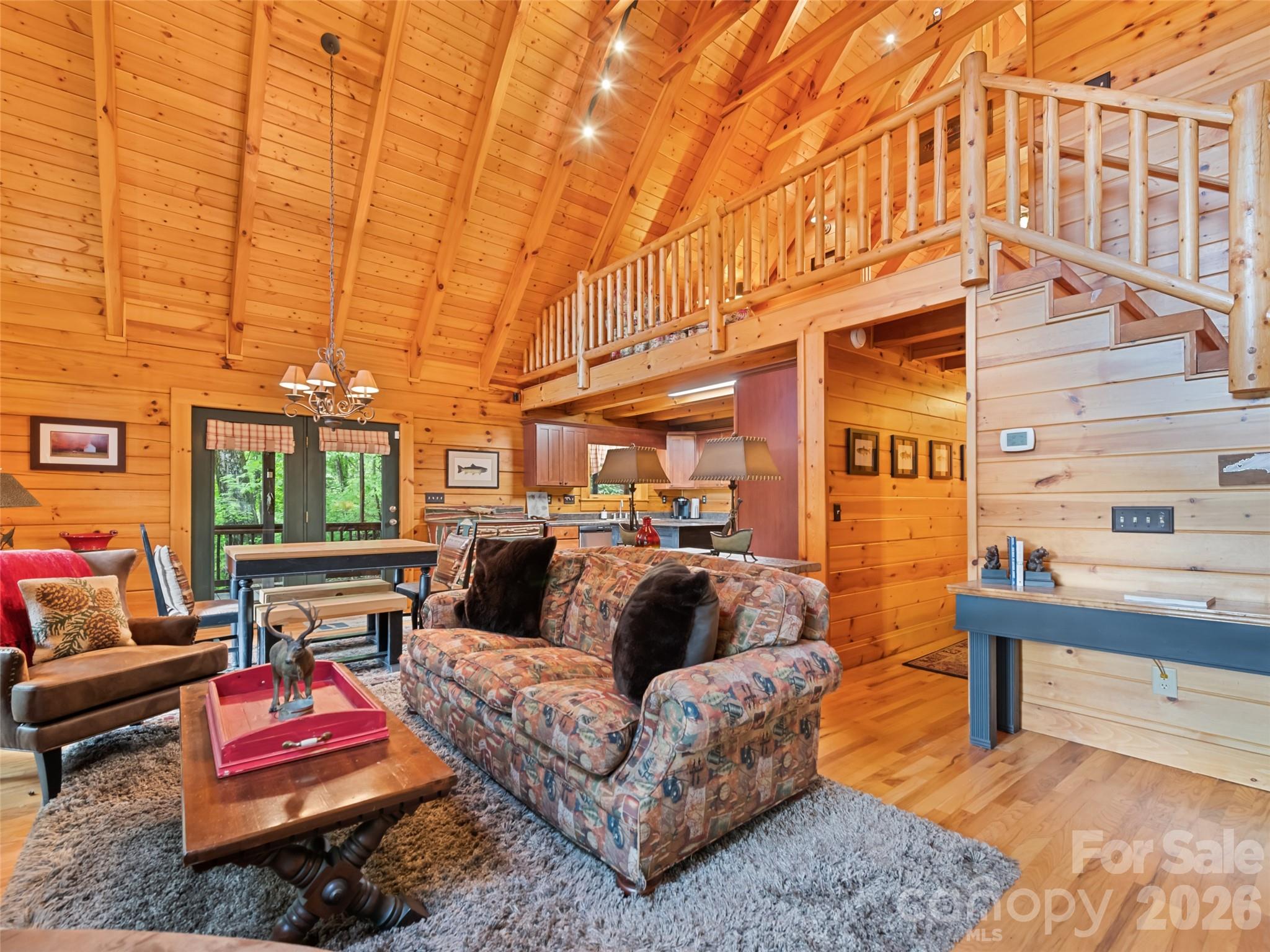 Tucked away in the peaceful woods of Maggie Valley, this charming 2 bedroom, 2 bath log cabin offers the perfect blend of rustic mountain character and comfortable mountain living. Located at 297 Hidden Cove Road, this inviting 1.5-story cabin welcomes you with soaring cathedral ceilings, exposed beams, warm wood finishes throughout, and an open-concept floor plan designed for gathering and relaxing. The spacious kitchen features ample cabinetry, generous counter space, island seating, and flows seamlessly into the dining and living areas, creating an ideal setup for entertaining or enjoying quiet mountain evenings at home. The lofted upper level adds to the airy cabin feel while providing additional flexible living space. Both bedrooms and bathrooms offer comfortable accommodations for full-time living or a mountain retreat. A dedicated laundry/mud room adds convenience and functionality after a day spent exploring the mountains. Outdoor living truly shines here with multiple spaces to enjoy every season in the Smokies. Sip your morning coffee from the screened porch, unwind with a rocking chair and a good book on the covered porch, or take in the peaceful long-range mountain views from the open front porch. Surrounded by nature and tucked into a private wooded setting, this property offers the feeling of being away from it all while still remaining convenient to area attractions and amenities. Lovingly maintained and never used as a rental, this cabin has been cared for as a personal mountain getaway rather than an investment property. The home reflects pride of ownership throughout and offers the authentic log cabin experience so many buyers are searching for in Maggie Valley. Whether you are looking for a full-time residence, private second home, or future vacation retreat, this property offers timeless mountain charm and a setting that invites you to slow down and stay awhile. Conveniently located near downtown Maggie Valley, Waynesville, hiking trails, the Blue Ridge Parkway, Cataloochee Ski Area, dining, shopping, and year-round outdoor recreation.