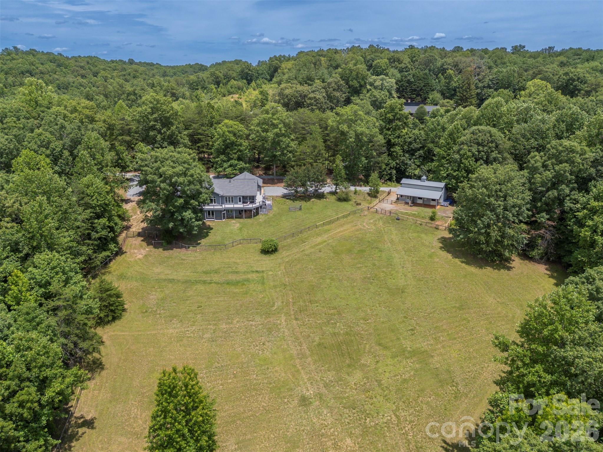 Set in the scenic foothills of Polk County at the end of a private road, this 10.73-acre equestrian retreat offers the rare combination of true privacy, direct trail access, and a turnkey two-horse setup in the heart of Western North Carolina.
Three bedrooms and three full baths flow across a thoughtfully designed single-level floor plan, with large windows throughout that frame the natural landscape and bring the outdoors in. The kitchen connects seamlessly to a breakfast area and screened-in porch where you can take in mountain views and watch your horses graze in the pasture below. An attached two-car garage adds everyday convenience, and the walk-out lower level — already fitted with windows, an exterior door, and plumbing — is primed for additional living space. Built by master builder John Edney, the 2,232-sq-ft one-level home is ready for your personal touches and upgrades. A new roof was installed in 2023, and the dual fuel HVAC was replaced in 2024. 
For equestrians, this property is purpose-built for the lifestyle. The FETA trail system runs directly along one side of the property, putting some of the most beautiful riding in Western North Carolina — including the waterfall at Stoneybrook — right at your doorstep. A walking trail loops the pasture, perfect for morning strolls with the dogs. The two-stall Morton barn features a concrete aisle, spacious 12x12 stalls, a tack room with a washer and dryer, and a full bathroom, making daily horse care as comfortable as it is efficient.
Privacy like this is hard to find. No through traffic, no neighbors in sight — just you, your horses, and over 150 miles of FETA trails waiting to be explored.