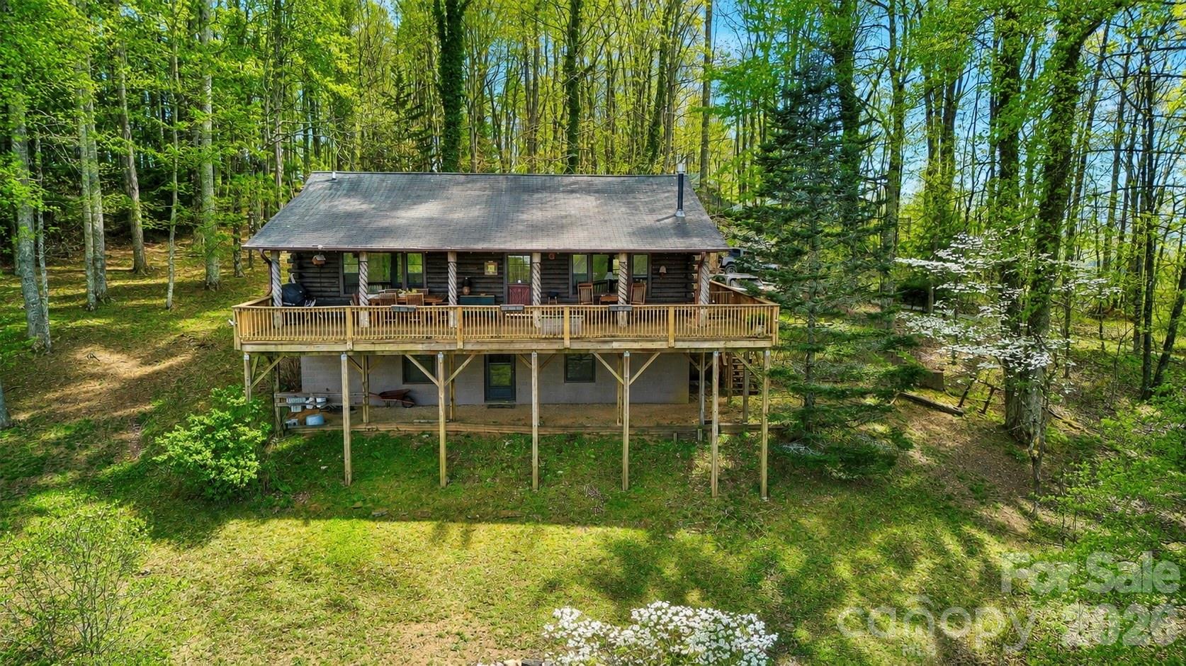 Above the Clouds - near Little Switzerland NC ! Custom log cabin featuring spectacular Long-Range views from Roan Mountain to the Unaka Range, with seasonal views of Mount Mitchell. This mostly furnished 2BR/2BA retreat offers oak hardwood floors, custom built-ins, expansive windows, and a massive 40' x 16' deck designed to capture unforgettable mountain sunsets plus a custom built . Unique artist-crafted deck posts from a Penland School of Craft artisan add character and charm. Full basement is plumbed and ready for expansion. Community water, ADT security system, circular drive, and low-maintenance yard. Just minutes from the Blue Ridge Parkway and Little Switzerland. Perfect as a mountain getaway, full-time residence or vacation rental. Rare combination of breathtaking views, privacy and future potential.
What is the elevation?  3,599 feet 
How many acres?         1.39 Acres
Is there fiber internet/high-speed internet?  Yes, Zito media; 
Any successful rental history? Owners did not rent-but future owner do have that option.
Distance to Asheville and Charlotte?  Charlotte 2-Hours; Asheville 1-Hour