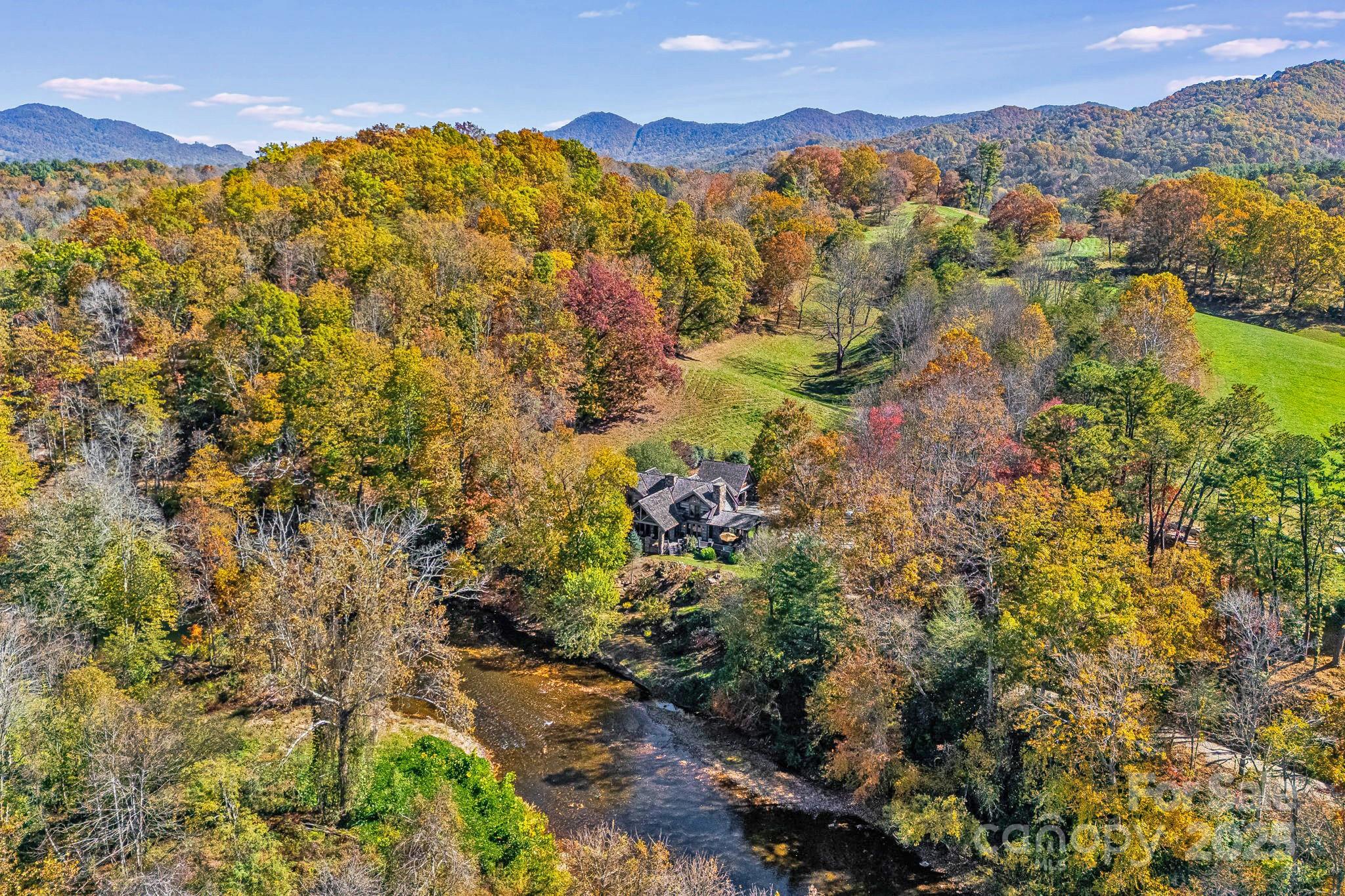 Price improvement! Discover this Exceptional Riverfront Estate on 11+ acres. An incredible private setting for this amazing lodge style home overlooking the Pigeon River with sweeping river & mountain views! The craftsmanship throughout this home is unparalleled. Majestic great room with cathedral beamed ceilings and stone fireplace. Massive hand-hewn logs and stonework. Spacious primary bedroom with fireplace and luxurious bath on main level. An inspiring chef's kitchen with Viking and Sub-Zero appliances open to the elegant dining area. Two guest bedrooms each with fireplaces, & baths with soaking tubs and showers. A generous loft provides flexible space for game room or office. Enjoy spacious covered porches with stone fireplace overlooking the river for great outdoor living. Carport with studio/bedroom and bath above. The land is a harmonious mixture of open pasture, woods and riverfront with a large swimming hole, great fishing and paddle sports! House and studio/carport in beautiful location overlooking river and not in flood plain. The location offers both seclusion and convenience just 15 minutes to Waynesville and 30 minutes to Asheville. This special property is where luxury meets nature and creates the perfect mountain retreat!