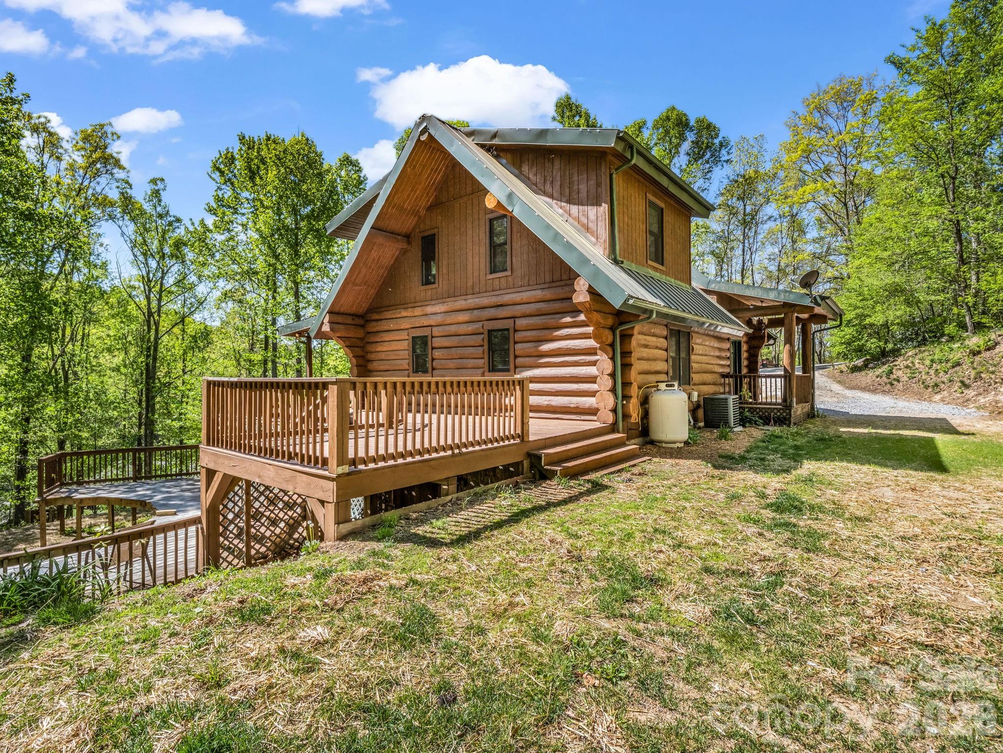 Come home to a beautiful log cabin situated on a rolling hillside with several recent upgrades. Inside find beautiful hardwood floors, vaulted ceilings, exposed wood beams, and natural light streaming in through plenty of windows. The upstairs loft area holds the primary bedroom with a full en-suite bathroom. The main level features a spacious great room with large windows, and a kitchen featuring stainless steel appliances,  and one bedroom.

Outside you're greeted with privacy and surrounded by nature's beauty. Sip coffee on the large covered porch that turns into an open wrap around and connects to the large side deck. Just below you'll see decking that used to encompass an above ground pool that has since been removed. This space is ready for a new one to be installed, or the perfect spot to expand your outdoor living with more entertainment space! On the basement level, you'll also find a second refrigerator along with a bedroom and tons of storage/office space that walks out to the lower covered patio area. All of this just 20 minutes from downtown Hendersonville, and 15 minutes to I-26, grocery stores and Advent hospital, giving you the perfect balance of convenience and quiet serenity. Schedule your showing today!
