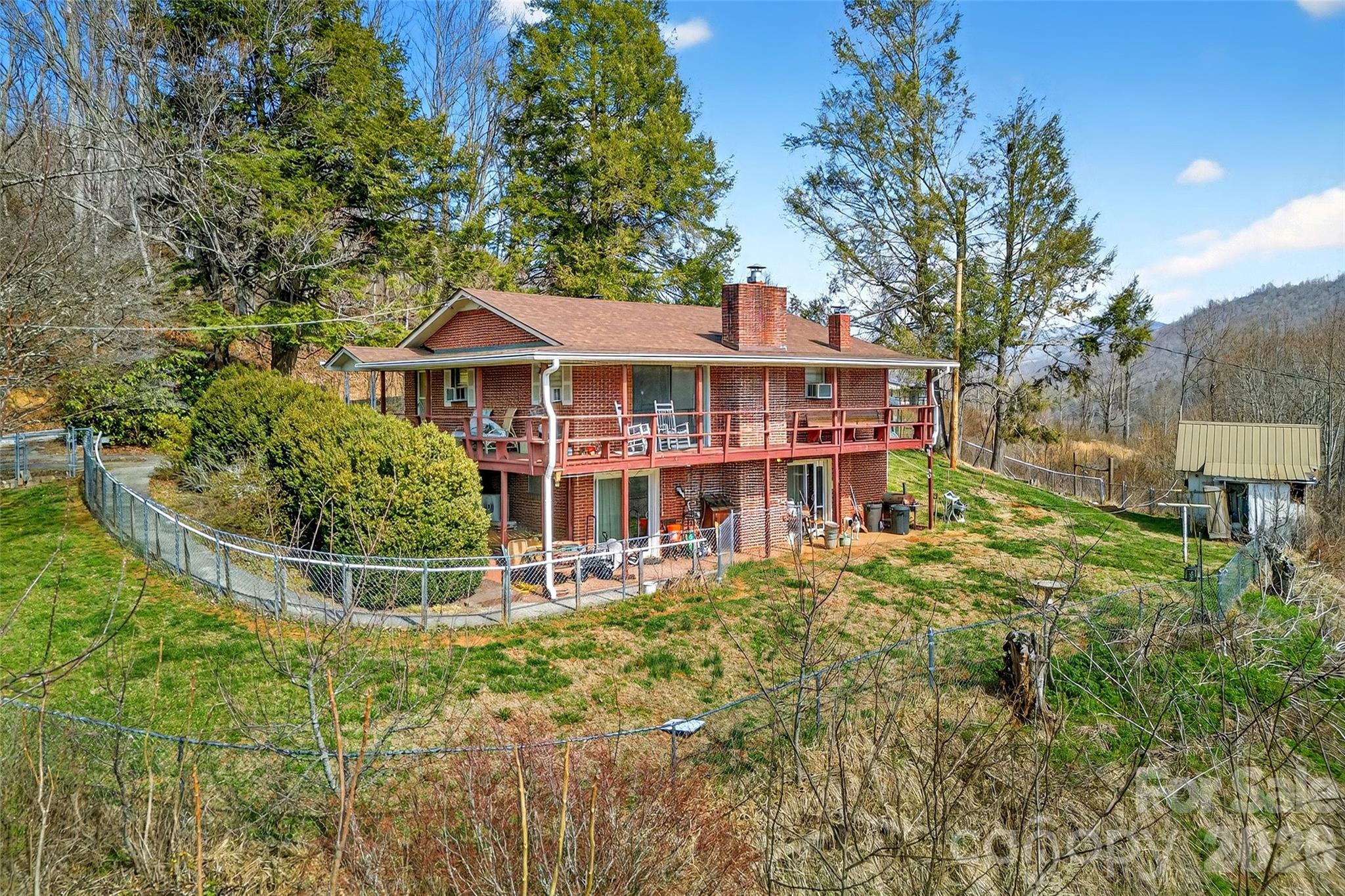 Welcome to this charming two-level brick home featuring 3 bedrooms plus a versatile bonus room or office and 2 full baths, all complemented by beautiful views. With separate entrances on each level, this property offers excellent potential for a two-level rental with the addition of a small upstairs kitchen. Home has a new roof.  Large barn on property for extra space. Enjoy easy paved access leading to a convenient circular drive. A fenced yard off the lower-level patio provides added functionality. Enjoy peace of mind with a whole home generator.  This place is about to pop with colors of beautiful rhododendron and other native flora.