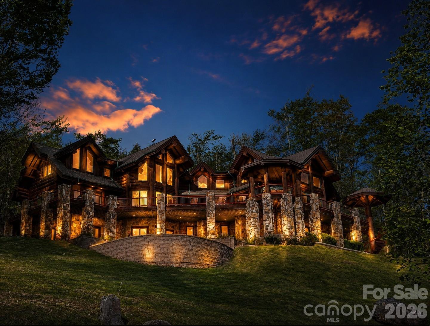 FIRST TIME ON THE MARKET! This extraordinary custom-built mountain retreat showcases impressive 14-inch lodgepole pine construction, soaring cathedral ceilings, expansive interior log accents, and dramatic floor-to-ceiling windows that perfectly frame breathtaking long-range mountain vistas! Privately situated on more than two south-facing acres, the home is bathed in natural light and offers unparalleled panoramic views with unforgettable sunsets enjoyed year-round. The open-concept main level is designed for both comfortable living and effortless entertaining, featuring a chef's kitchen, spacious dining room, spectacular two-story great room anchored by a floor-to-ceiling stone-stacked fireplace, powder room, laundry room, and an elegant primary suite complete with a walk-in closet and spa-inspired bath boasting a Jacuzzi tub, walk-in shower, and radiant heated floors. Perched above the great room, a loft-style office overlooks the living space and adjoins a second primary suite featuring an ensuite bath and walk-in closet. The opposite wing of the upper level offers two additional bedrooms, two full baths, a sitting area, and generous storage space, providing privacy and comfort for family and guests. The welcoming lower level is truly an entertainer's dream, featuring a spacious recreation room with a floor-to-ceiling stone fireplace, pool table, custom bar adorned with live-edge countertops, full bath, media room, exercise room with half bath, and a relaxing sauna. French doors open to a private covered patio, tranquil pond with fountain and a cozy outdoor fire pit. Outdoor living is equally impressive. The expansive wraparound deck captures endless mountain views and provides the perfect setting for al fresco dining, evening cocktails, and nightly stargazing. Additional highlights include a covered front entry, an octagonal gazebo housing a hot tub, and a custom spiral staircase with artisan-crafted railing.  A TRUE HAVEN OF SERENITY, this remarkable property is located just moments from the new Hatley Pointe ski lifts and the Wolf Laurel clubhouse, while remaining only ten minutes from I-26 and approximately fifteen minutes from grocery shopping. Ideally situated, enjoy scenic four-lane drives of approximately 35 minutes to either Asheville, North Carolina, or Johnson City, Tennessee, offering the perfect balance of mountain seclusion and everyday convenience.
