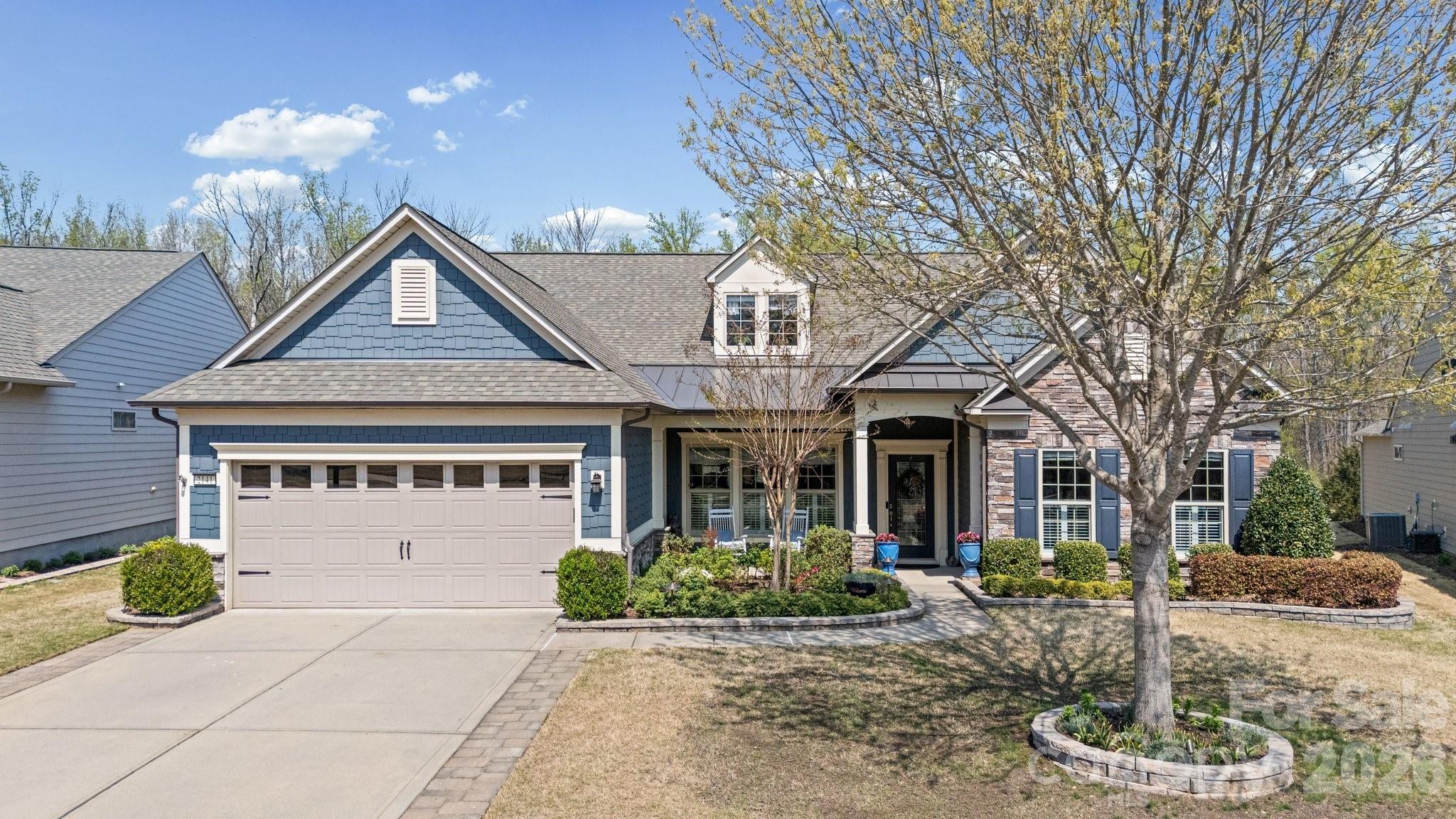 PRICE IMPROVEMENT - Welcome Home . . . The stunning two-story Tangerly Oak model offers 3,865 square feet of beautifully designed living space.  Perfectly situated in Village E, it is just a short walk to all the amazing amenities Carolina Orchards 55+ premier community offers. From the minute you enter in through the leaded glass front door you will be impressed by the thoughtful layout, elegant finishes, and one-of-a-kind designer touches throughout this waterfront home. First floor boasts two spacious primary bedroom suites, each with its own private bath and walk-in custom closets.   A front office w/glass doors is ideal for work or quiet reading. The laundry room has a sink and cabinets, washer/dryer included,  A beautifully appointed kitchen w/staggered white cabinets, quartz countertops, stainless appliances, stainless direct-vent hood, gas cooktop, walk-in pantry, breakfast eating area, large island w/pendant lights and seating, FARM sink (my favorite), open to the dining area and great room w/corner stone fireplace. Move into two rooms overlooking the private backyard - one looking out onto the wooded area - the other overlooking the pond.  Head out to the custom-designed patio and check out the pond view and all nature has to offer.  Back inside let's go upstairs to the loft area, spacious bedroom w/sitting nook, large storage closet, and full Bath . . . Don't forget to check out the walk-in attic storage.  The garage with epoxy floor is a two car+tandem area perfect for your golf cart, work bench, or storage.  Professionally landscaped - full sprinkler system with drip zones, lawn maintenance included, and lots of hardscape - paver extensions on the driveway complete the perfect home. This home combines luxury, convenience, and comfort in every detail.  Tons of amenities--indoor/outdoor pools & hot tubs, 8 lit pickleball courts, 4 lit tennis courts, 2 bocce courts, dog park, playground, fitness center, full time activities director. Come join us in the Orchards. It's a great place to call home. Don't miss this one.