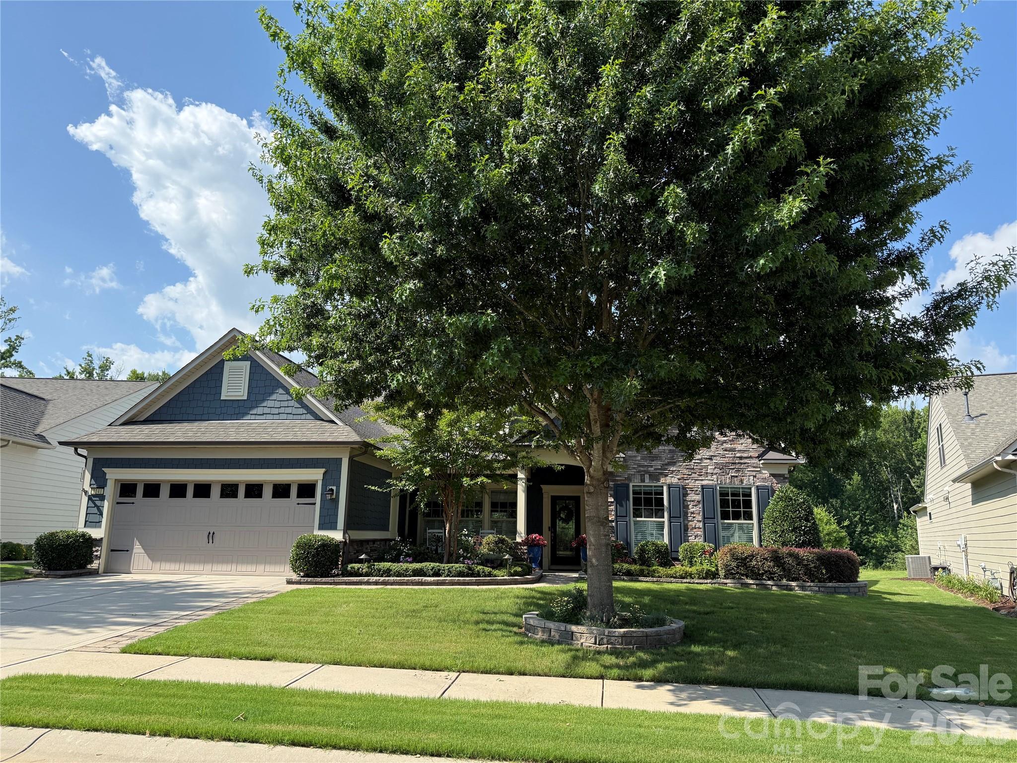 PRICE IMPROVEMENT - Welcome Home . . . The stunning two-story Tangerly Oak model offers 3,865 square feet of beautifully designed living space.  Perfectly situated in Village E, it is just a short walk to all the amazing amenities Carolina Orchards 55+ premier community offers. From the minute you enter in through the leaded glass front door you will be impressed by the thoughtful layout, elegant finishes, and one-of-a-kind designer touches throughout this waterfront home. First floor boasts two spacious primary bedroom suites, each with its own private bath and walk-in custom closets.   A front office w/glass doors is ideal for work or quiet reading. The laundry room has a sink and cabinets, washer/dryer included,  A beautifully appointed kitchen w/staggered white cabinets, quartz countertops, stainless appliances, stainless direct-vent hood, gas cooktop, walk-in pantry, breakfast eating area, large island w/pendant lights and seating, FARM sink (my favorite), open to the dining area and great room w/corner stone fireplace. Move into two rooms overlooking the private backyard - one looking out onto the wooded area - the other overlooking the pond.  Head out to the custom-designed patio and check out the pond view and all nature has to offer.  Back inside let's go upstairs to the loft area, spacious bedroom w/sitting nook, large storage closet, and full Bath . . . Don't forget to check out the walk-in attic storage.  The garage with epoxy floor is a two car+tandem area perfect for your golf cart, work bench, or storage.  Professionally landscaped - full sprinkler system with drip zones, lawn maintenance included, and lots of hardscape - paver extensions on the driveway complete the perfect home. This home combines luxury, convenience, and comfort in every detail.  Tons of amenities--indoor/outdoor pools & hot tubs, 8 lit pickleball courts, 4 lit tennis courts, 2 bocce courts, dog park, playground, fitness center, full time activities director. Come join us in the Orchards. It's a great place to call home. Don't miss this one.