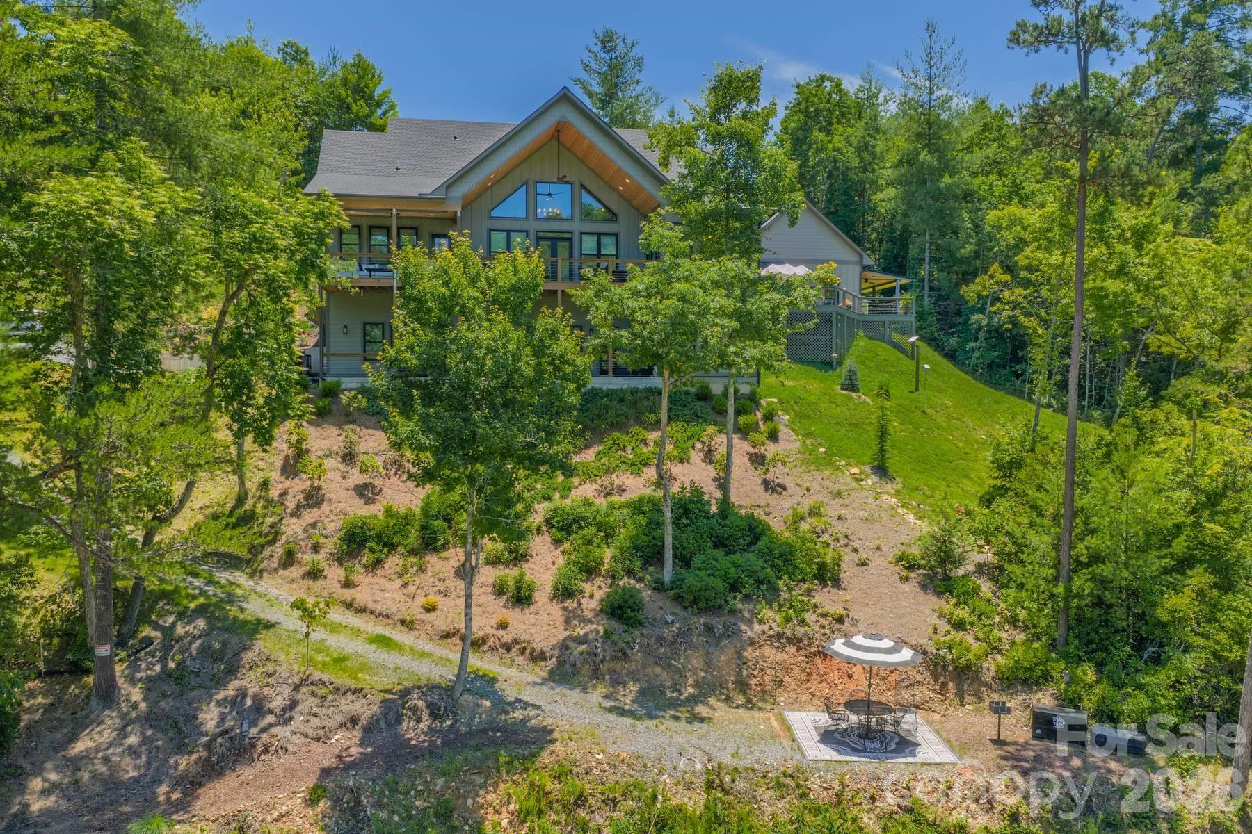 Some homes are built for resale. Others are built for retirement. Very few are built by someone who spent a lifetime in the construction industry, understood every system behind the walls, and intended to live there forever.
The owner, a former builder and former owner of one of the region’s most respected HVAC companies, designed and constructed this residence as his personal forever home. Every decision—from the foundation and insulation to the mechanical systems and lake access—was made with longevity, comfort, efficiency, and ease of ownership in mind.
Nestled along Fontana Lake, the property offers a unique combination of quality construction, practical luxury, and waterfront enjoyment. This home experiences very little boat traffic and as a  result is a peaceful setting where the water remains inviting and accessible. The home offers approx 4,100 heated square feet and is currently configured as four bedrooms plus a loft. The main level features a spacious primary suite, an additional guest bedroom, and a separate full bath, allowing for comfortable main-level living. Upstairs, the loft serves as a flexible space for an office, overflow sleeping area, or studio and has a half bath. The lower level expands the home’s versatility with two bedrooms, a full bath, fitness room, mud room, and additional storage space. Heated floors throughout the lower level provide exceptional comfort year-round. What truly separates this property from many luxury homes is what lies beneath the surface. The foundation was built with additional reinforcement. The exterior is clad entirely in Hardie Board siding and soffits for long-term durability and low maintenance. Spray-foam insulation was installed throughout the structure, improving comfort while reducing energy consumption. The owner engineered and installed a sophisticated three-zone HVAC system with smartphone controls and outside-air circulation for enhanced efficiency and indoor air quality. Despite the home’s size, the owner reports the highest monthly power bill has been approximately $182. Throughout the home, quality finishes continue the theme of intentional construction. Energy-efficient windows fill the interior with natural light, while Hunter Douglas window treatments provide privacy and comfort. The kitchen features Bosch appliances, including an induction cooktop and quiet dishwasher. A water purification system, while the well produces more than 40 gallons per minute. The seller plans to install a holding tank and provide a shared well agreement for the adjacent home currently under construction. Outdoor living was designed with the same level of thoughtfulness. The upper covered deck offers a private retreat for enjoying mountain mornings, lake views, and cool evening breezes. The lower deck is accessible from both the interior and exterior of the home, making it convenient for guests returning from the water. A paved circular driveway provides easy arrival, departure, and ample parking. A detached two-car garage complements the additional lower-level garage and storage area, offering plenty of room for vehicles, boats, lake toys, tools, and outdoor equipment. The walk to the water is one of the property’s most appealing advantages. Unlike many mountain lakefront homes where access can be steep and challenging, the path to the shoreline is gentle, walkable, and suitable for side-by-side access. TVA approval is already in place for an 8’x12’ wooden dock landing. The current dock system is mounted on wheels and designed to adapt to seasonal water levels. Additional outdoor features include a grilling area, firepit, and landscaping.  For buyers seeking a lakefront home, this offers something increasingly difficult to find: a residence built not for resale, but to satisfy the exacting standards of the person who intended to spend the rest of his life there.