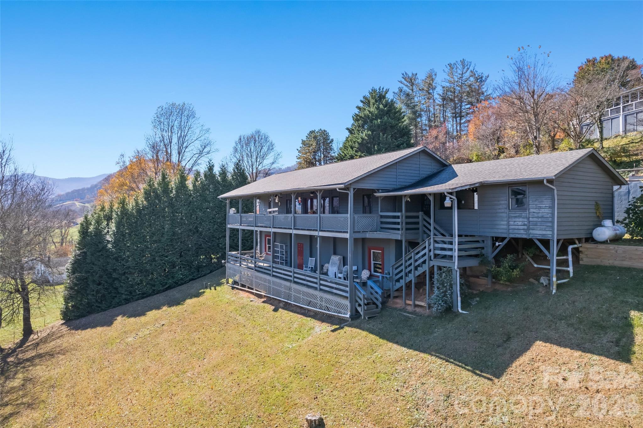 Wide-Open Mountain Views in Waynesville! Enjoy views from the covered deck and outdoor cooking area of this charming 2-bedroom, 2-bath home, built in 1993 and set in a peaceful country setting just 20 minutes from downtown Waynesville. This one-level home offers easy living, a spacious great room, a propane stove-style fireplace, a kitchen island, and large windows that fill the space with natural light and showcase the mountain scenery. Both bedrooms include private ensuite baths and walk-in closets. Step outside to the wraparound deck—perfect for relaxing or entertaining—with a covered outdoor cooking area ready for your grill and an outdoor portable gas fireplace. At 2,600+ ft elevation, this home enjoys cool mountain breezes and southeast-facing views ideal for sunsets. Additional features include ample parking for 2–3 cars, Zito internet/TV, city water, low annual HOA dues of just $120 (for road maintenance only). No city taxes and not within city limits. Short-term rentals are allowed.
