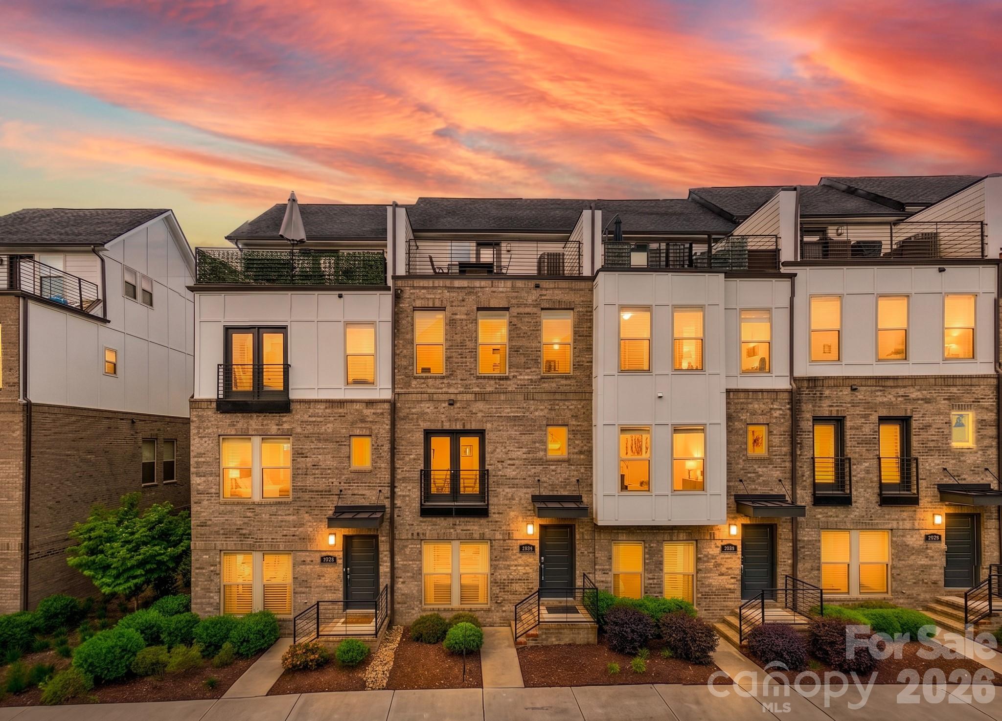Welcome to 15036 New Amsterdam Lane — a statement-making, four-story townhome in Central Point, perfectly positioned between Uptown and Plaza Midwood with NoDa just minutes away. This is true “lock-and-leave” city living with a luxury feel: sleek design, generous square footage, a 2-car garage, and an expansive rooftop terrace that turns every weekend into an event.

The main living level is designed to impress and to live well. A wide-open floorplan creates effortless flow from the kitchen through the dining and living spaces, so everything feels connected, bright, and intentionally laid out for entertaining. The kitchen anchors the home with a large social island (the kind people naturally gather around), abundant workspace, and clean, modern finishes that feel elevated without being fussy. Whether you’re hosting dinner, game day, or a casual wine night, the layout works—open, social, and comfortable.

Upstairs, the owner’s suite is a true retreat with the space you want and the storage you need. Large walk-in closets, a spacious bedroom, and a well-appointed bath create that private “end of the day” sanctuary. Additional levels give you flexibility that’s hard to find in city living—perfect for a guest suite, home office, workout space, or a dedicated media lounge. And unlike many urban townhomes, this one delivers on the practical side too: tons of storage throughout, smart closet space, and a garage that makes daily life easier.

Then there’s the crown jewel: the rooftop terrace. It’s expansive, private, and built for the lifestyle—sunset dinners, weekend brunch, string lights and music, or simply a quiet moment with skyline vibes. Create a full rooftop lounge with seating, dining, and greenery and you’ve got an outdoor living space that feels like a high-end penthouse—without the high-rise.

Location is the finishing touch. Central Point places you in the middle of Charlotte’s most energetic districts, where some of the city’s best dining, cocktail spots, coffee, and breweries are all within easy reach. You’re also one block from two major perks: immediate access to 277 for quick commutes, and the Little Sugar Creek Greenway for walking, running, or biking through the city’s parks and neighborhoods. It’s the kind of address that makes Charlotte feel smaller—in the best way—because everything is close.

If you want luxury, flexibility, and a true urban lifestyle with a rooftop terrace that steals the show, 15036 New Amsterdam Lane delivers.