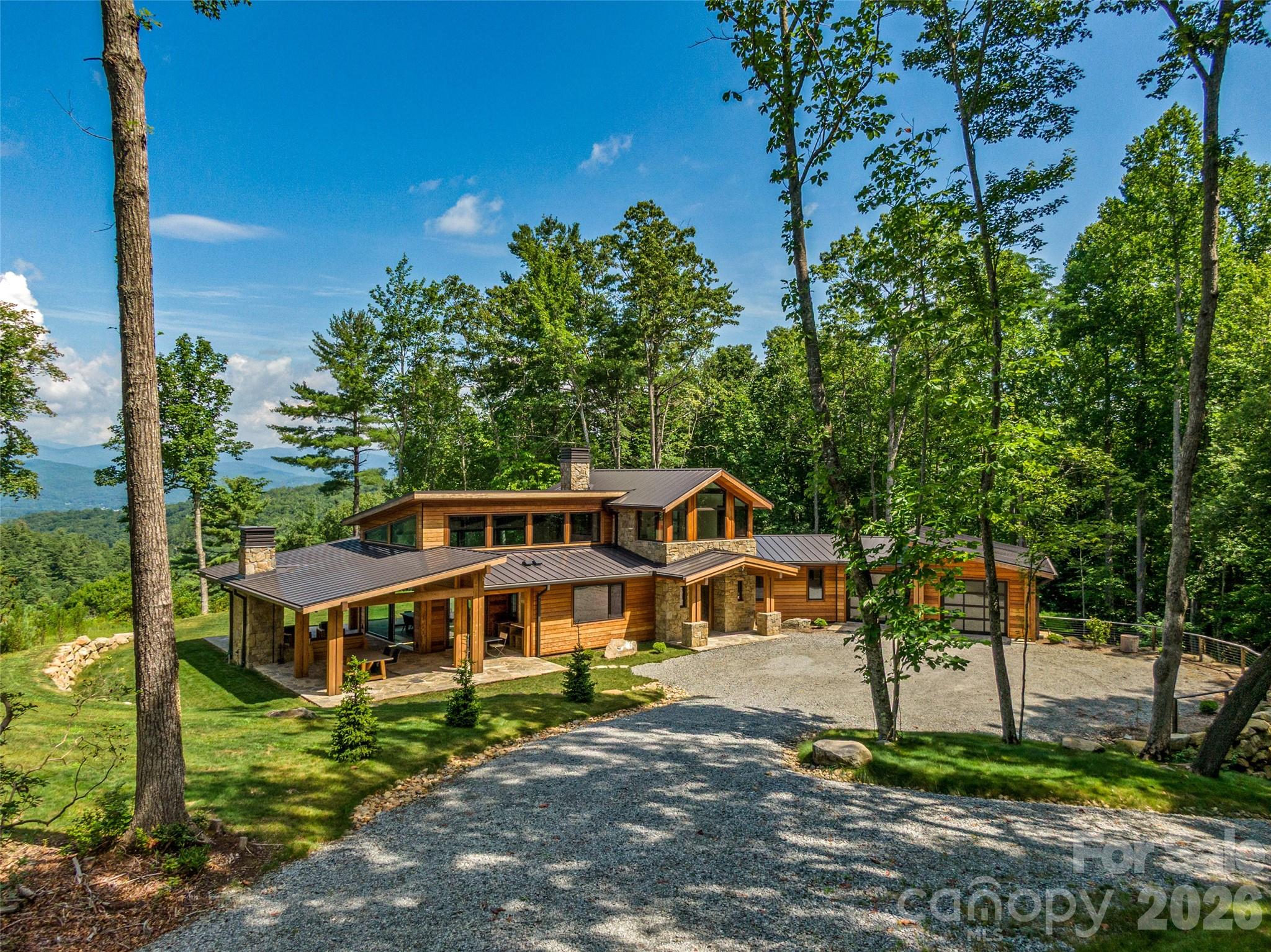 Designed by Platt Architecture, this exquisitely crafted residence in the Eagle Lake community just outside Brevard offers refined modern living in a sunlit, airy setting with long-range Blue Ridge Mountain views and access to one of Western North Carolina’s most serene private lakes.

Exceptional in both design and execution, the home features hardwood floors, a striking stone fireplace, and a chef’s kitchen appointed with marble surfaces and custom finishes. A sculptural floating wood staircase serves as both architectural centerpiece and functional design, complemented by a substantial marble-topped island anchoring the kitchen.

The great room soars with dramatic ceiling height and walls of glass framing sweeping Blue Ridge vistas, seamlessly integrating the kitchen and dining areas into an open layout designed for both effortless daily living and elegant entertaining. The space extends to a covered flagstone outdoor living area, anchored by a commanding stone fireplace—ideal for year-round enjoyment.

Each bath is individually designed with curated tilework, glass elements, and high-end fixtures. The primary suite is defined by two walls of floor-to-ceiling windows, capturing breathtaking views of the surrounding forest and Blue Ridge Mountains beyond.

A short walk leads to private Eagle Lake, a pristine 32-acre mountain lake offering swimming, paddling, and fishing, along with a community beach, playground, and covered picnic pavilion. Residents also enjoy open recreation areas, trails, and expansive preserved green space.

Downtown Brevard—known for its vibrant dining, arts, and music scene—is just 15 minutes away, while Cedar Mountain, 13 minutes in the opposite direction, offers charming local shops, dining, and seasonal live music at the gateway to DuPont State Forest.