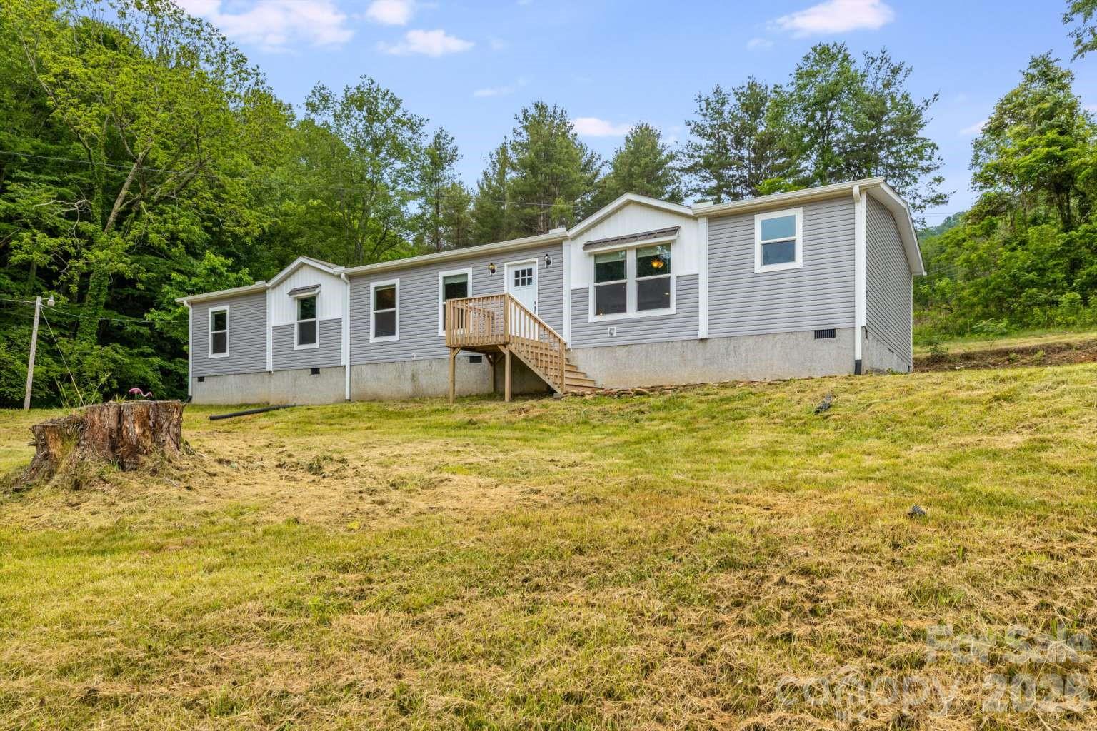 Just imagine yourself enjoying modern mountain living in this beautifully maintained 2022 home located in the peaceful Clyde area near Hwy 209. Featuring stylish modern upgrades throughout, this move-in ready home offers an inviting open-concept great room with seamless living, dining, and kitchen spaces perfect for entertaining or relaxing. Thoughtful touches including barn doors, a spacious laundry room, mud room, and split-bedroom layout add both charm and functionality. The private primary en suite is thoughtfully separated from the secondary bedrooms for added comfort and privacy. Situated on a cleared and mostly level lot with easy year-round access, this property offers plenty of usable outdoor space to enjoy. Conveniently located near Waynesville, Maggie Valley, the Blue Ridge Parkway, hiking, dining, breweries, and endless outdoor recreation, 22 Split Pine Cove offers the perfect blend of comfort, convenience, and mountain lifestyle.