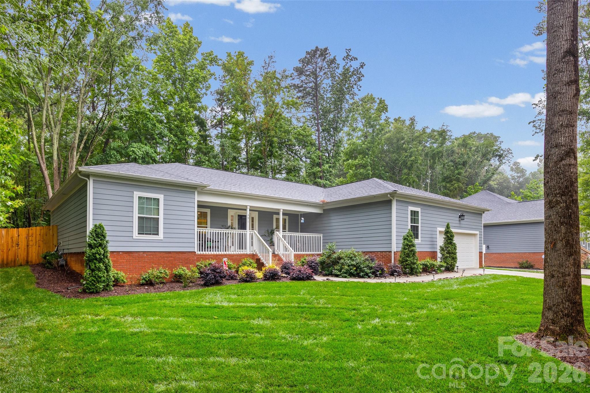 Imagine pulling up to this charming 2022-built ranch home, where a welcoming front porch and meticulous landscaping invite you inside to a bright, wide-open floor plan. The heart of the home centers around a beautifully designed kitchen featuring granite countertops, a tiled backsplash, and a massive breakfast bar that effortlessly handles a crowd—perfect for casual morning coffee or hosting weekend get-togethers. The main living space feels airy yet cozy, anchored by a fireplace and wrapped in modern finishes like wide-plank flooring and recessed lighting. Designed with a split-bedroom layout for maximum privacy, the primary suite serves as an exceptionally spacious retreat, complete with an elegant tray ceiling, a generous walk-in closet, and a pristine bathroom featuring dual sinks and a tiled shower. Everyday convenience is built right in, from the large laundry room with a dedicated sink to the extra storage room that can double as a flex space. Step out back to find your own private escape: a peaceful screened porch that opens to a grilling patio and a lush yard. Sitting on over half an acre with a secure, thoughtfully configured fence and backed by mature trees, you have plenty of room to play, garden, or simply unwind.