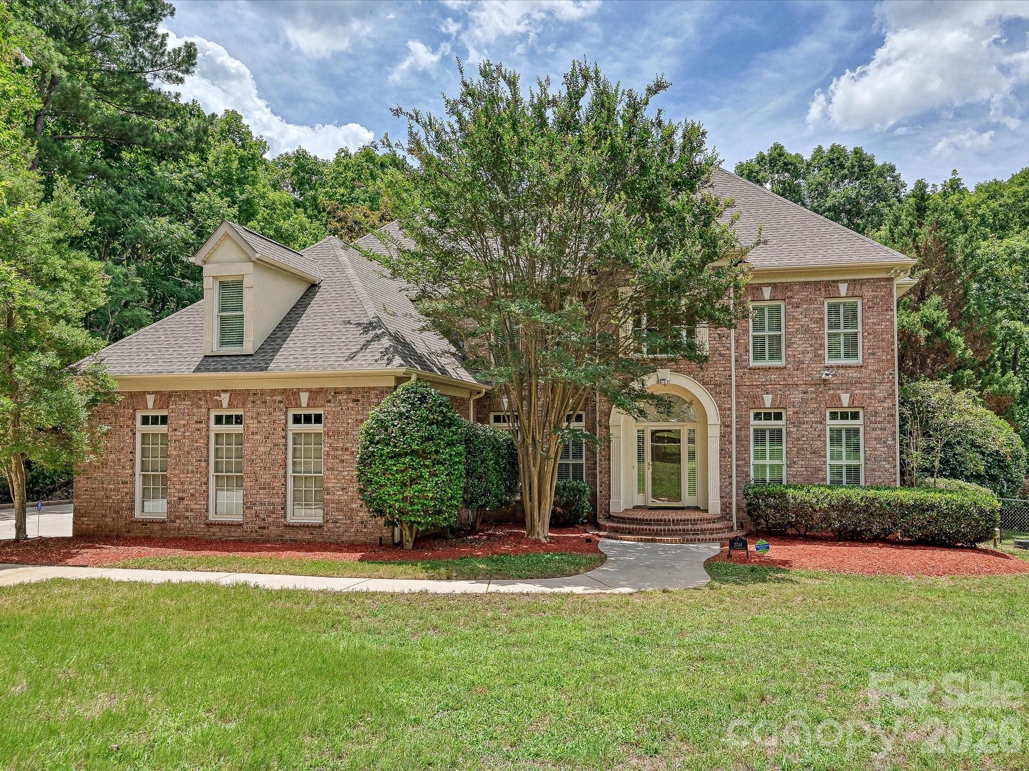 Every once in a while, a truly exceptional property comes along. Nestled on a secluded 1.5-acre lot in Chester, this magnificent brick executive home offers the perfect blend of privacy and luxury.  Inside, site-finished hardwood floors welcome you into a stunning two-story foyer, highlighted by a graceful staircase with wrought-iron balusters. The entry is flanked by a formal dining room and double French doors leading to a private home office. A main-floor full bath adds incredible flexibility for guests or multi-generational living.
The foyer flows effortlessly into a breathtaking two-story great room, where soaring, south-facing windows frame a cozy gas fireplace. Tucked to the side is a quiet study with custom built-in shelving—ideal for a reading nook or secondary workspace. The open-concept layout is an entertainer’s dream, centering around a premium kitchen equipped with a new GE Profile built-in stainless steel refrigerator, Thermador electric cooktop, and a built-in microwave/oven combination. Step from the kitchen into the enclosed sun porch, which overlooks your private backyard oasis: a heated, salt-water inground Gunite pool. Upstairs, the impressive primary suite serves as a true retreat, featuring a decorative tray ceiling, a massive walk-in closet with custom shelving, and a spa-like luxury bath with a deep Jacuzzi tub and an oversized step-in shower. For ultimate convenience, the laundry room is located just steps away. The secondary bedrooms are equally impressive: one features a private en-suite bath and walk-in closet, while the third and fourth bedrooms share a spacious Jack-and-Jill bath. Spend your summers lounging by the pool or exploring the expansive, wooded grounds bordered by a tranquil creek. This is more than a home—it’s a lifestyle.