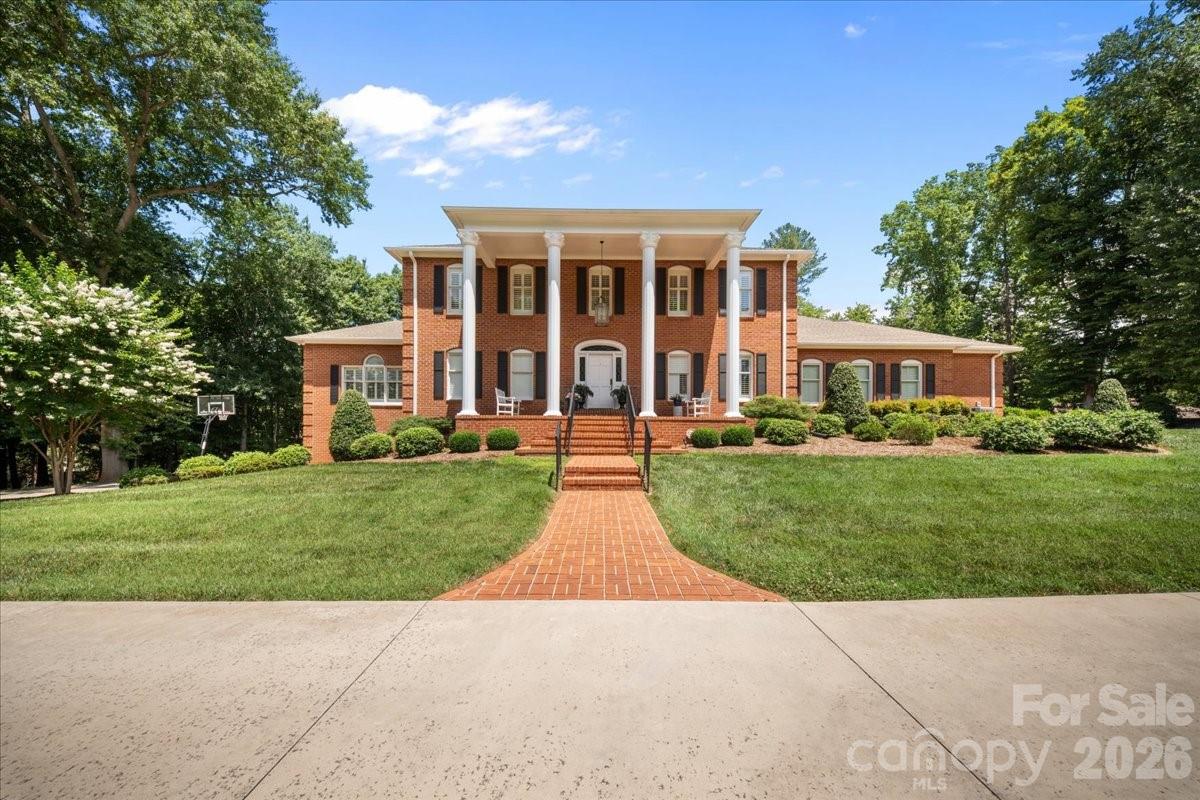 Welcome to this Southern estate situated within a beautifully landscaped and designed setting. This stately brick home impresses from the moment you arrive with its grand columned façade, circular driveway, manicured grounds, and exceptional curb appeal. Thoughtfully designed with both entertaining and everyday living in mind, this home offers the perfect balance for your family's needs. The expansive floor plan features a huge custom kitchen complete with premium finishes, abundant cabinetry, and generous workspace, flowing seamlessly into multiple gathering areas. Enjoy hosting in the private formal dining room, relax in the sun-filled sunroom, or spread out between the elegant formal living room and inviting family room. The, nearly one of kind, impressive main-level primary suite serves as a luxurious private retreat, featuring an oversized walk-in shower, spacious walk-in closet, and exceptional comfort and privacy. Accessibility and convenience were clearly prioritized, with an extremely accessible walk from the primary garage to the main level, making everyday living effortless. Upstairs, you'll discover almost an entirely separate home of its own, offering four spacious bedrooms, including an additional primary suite and another full bath. Whether accommodating a growing family, multi-generational living, or long-term guests, this thoughtfully designed upper level provides exceptional flexibility and space. The basement level offers even more possibilities and is perfectly suited for guests, teenagers needing their own space, or those family members and friends who love to stay for the weekend. With ample room to spread out, this additional space adds even more versatility to an already impressive home. Step outside to discover your own resort-style oasis. Spend those days lounging by the pool, then cool down and unwind beneath the covered patio overlooking the pool. As evening falls, retreat to the screened porch or enjoy gatherings on the extended uncovered patio while taking in the peaceful, private surroundings. Basically, if your family needs it, this home has it. And that's not all! This entire estate is located just minutes from downtown, offering the perfect display of convenience. Enjoy quick access to shopping, dining, and everyday amenities while still experiencing the peace and seclusion of your own retreat. Surrounded by mature trees and lush landscaping, this remarkable property offers an unparalleled combination of luxury and functionality.