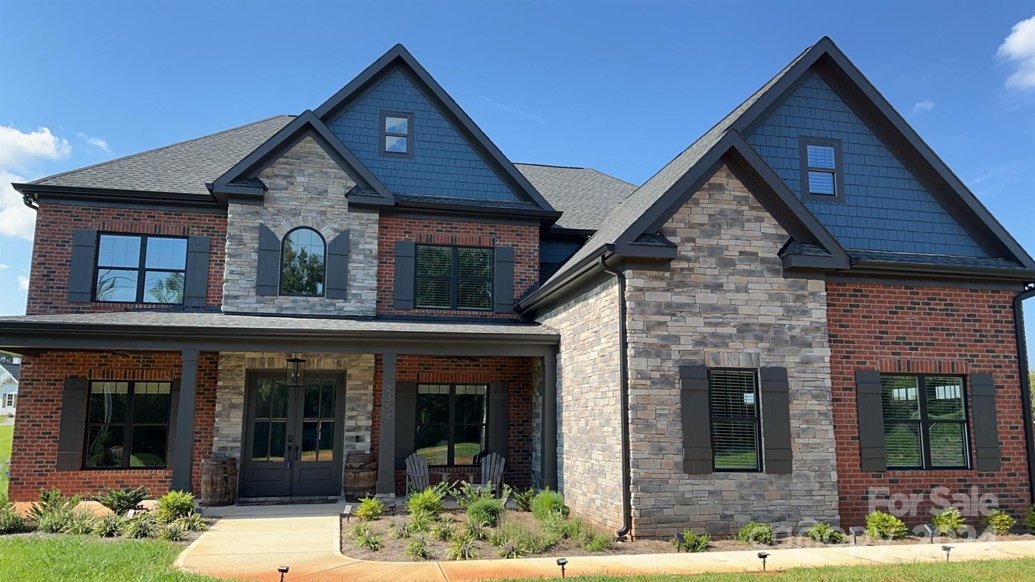 5+ acres brick NO HOA home offers a wealth of features! High, vaulted, and tray ceilings throughout, a minimum of 10ft on the 1st floor + 9ft on the 2nd. Chef's dream kitchen with a 7-burner gas range, double oven, and space for a wine fridge. 3-car oversized garage provides ample space and storage. 6 video cameras with 2-way talk and color night vision. 2-story grand room with a fireplace and a smart fan creates an inviting center of the home. Double sliding glass doors lead to the large covered patio with its own fireplace. Both fireplaces are TV ready and the instant tankless hot water heater, electronic shades, blackout blinds, and whole house water filter add convenience. Ceiling fans and fandeliers throughout. The primary bedroom is a retreat: spacious layout, chic ensuite bath, and a large walk-in closet. Gym/bonus room above garage. Backyard offers unmatched views and unique must-see natural rock formations! Faces South and in the Clover School district!
