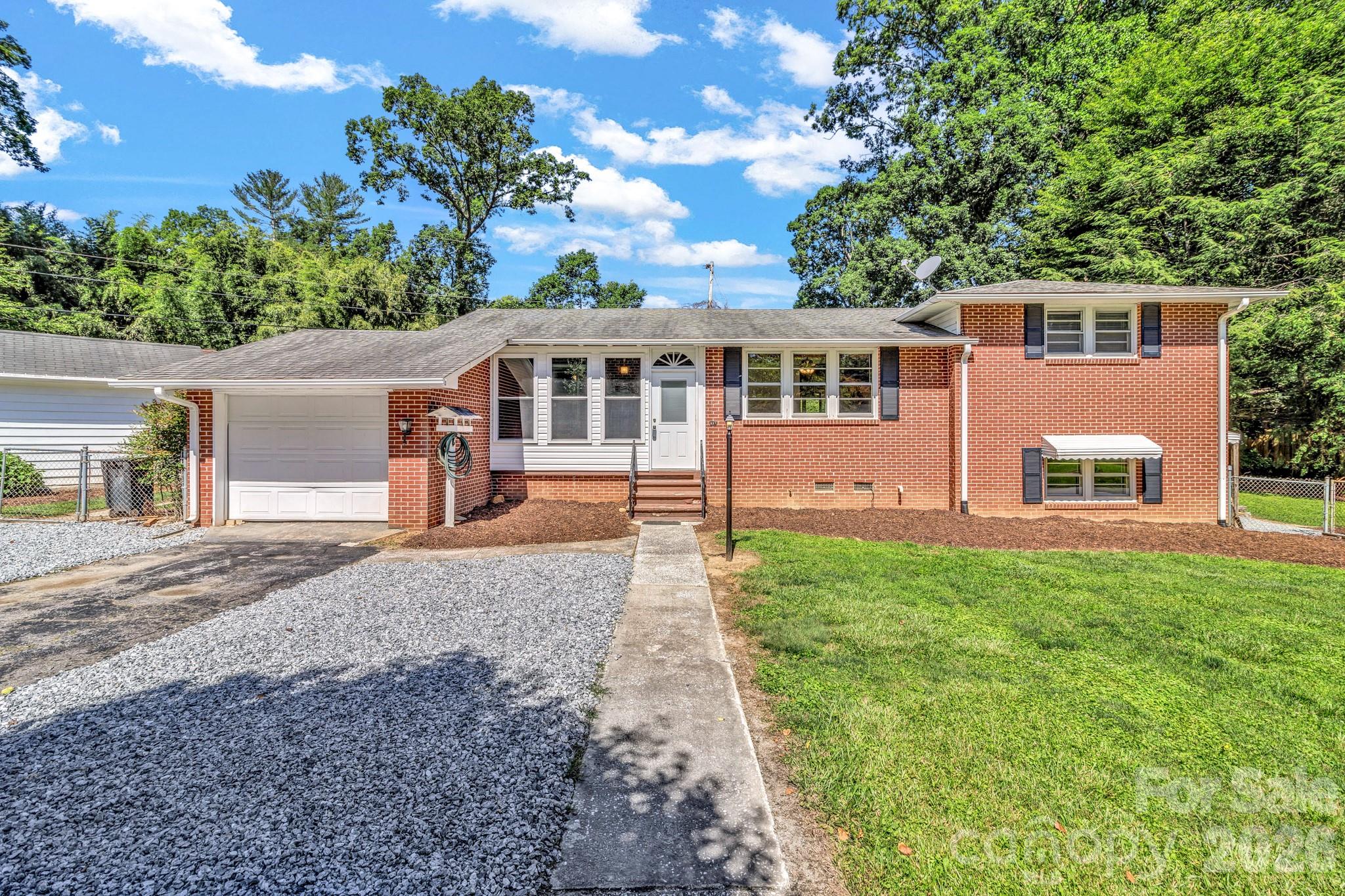 Welcome to 907 W Blue Ridge Road in East Flat Rock! This well-built brick home offers timeless character, solid construction, and plenty of opportunity to make it your own. Situated on a desirable corner lot, the property features beautiful hardwood floors throughout much of the main level, a covered and enclosed front porch perfect for relaxing year-round, and a bright sunroom overlooking the backyard. The main level provides comfortable living spaces that are move-in ready while offering room for future updates and personalization. The kitchen and baths retain their original charm, allowing the next owner to update at their own pace. Downstairs, you'll find a spacious partially finished basement with a woodstove, creating the perfect space for a den, recreation room, workshop, home office, hobby area, or additional flex space. The home is equipped with a heat pump providing heating and air conditioning, along with natural gas radiant heaters for supplemental warmth and comfort. Outside, the fenced backyard offers room for gardening, pets, and outdoor enjoyment. Additional improvements include a detached outbuilding, covered storage area with shed roof, and a one-car garage providing ample space for tools, equipment, and storage.

Conveniently located in East Flat Rock, this property offers a wonderful combination of character, functionality, and potential. Whether you're looking for your first home, an investment opportunity, or a property to update over time, this home is ready for its next chapter.