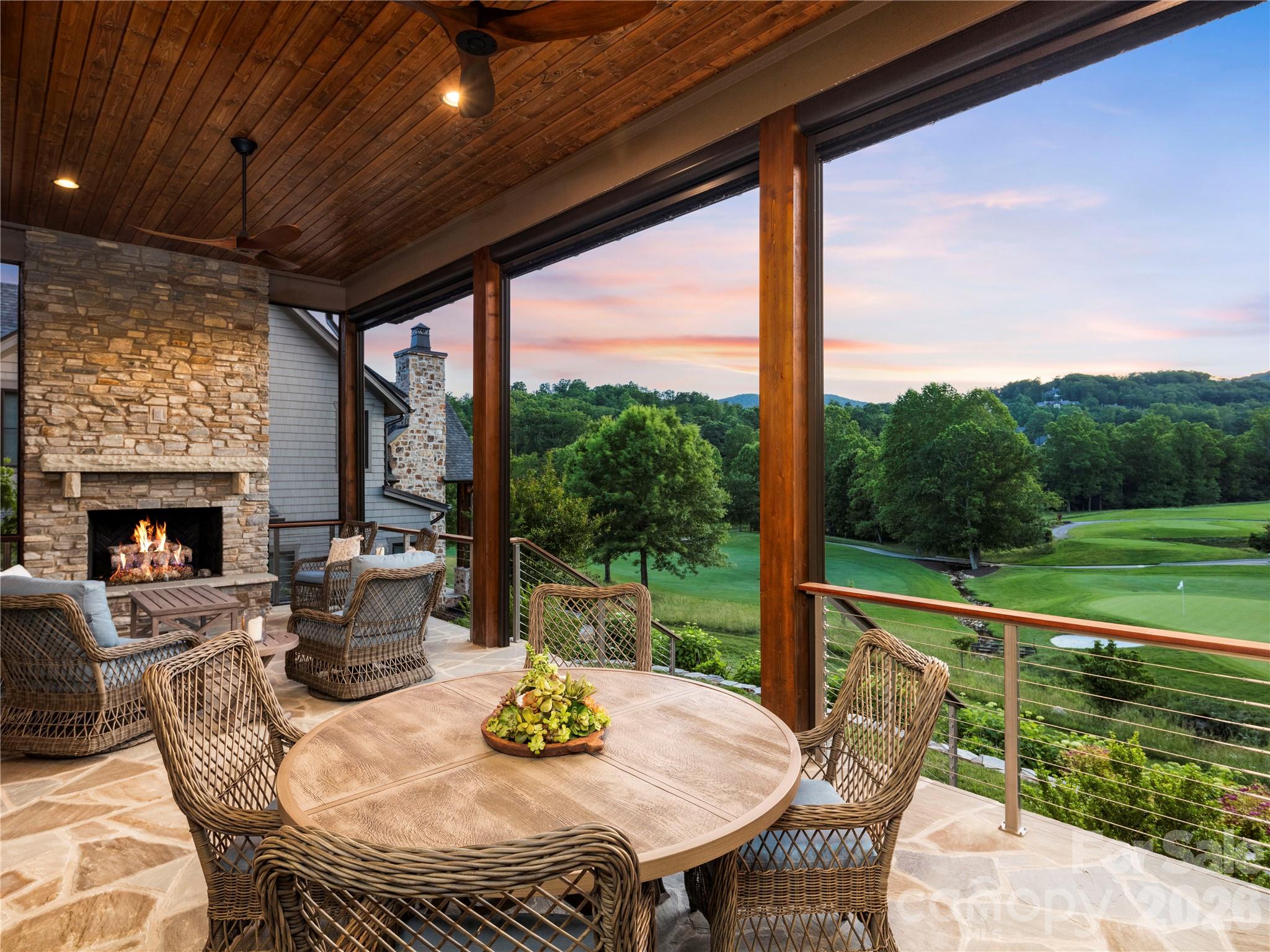 Nestled directly within the exclusive Club Village, just steps away from the community clubhouse, 103 Somerset Village Lane defines luxury living within The Cliffs at Walnut Cove. Situated along the 10th hole of the Jack Nicklaus Signature golf course—set to serve as the historic first hole for the upcoming PGA tournament—this sophisticated estate makes a grand first impression with its striking stone accents, pristine landscaping, and beautiful paver driveway. Inside, the open-concept main floor seamlessly blends elegance and comfort, highlighting an inviting living room anchored by a handsome stone-stacked fireplace and rich, exposed wood beams. The adjoining gourmet kitchen is a chef's dream, showcasing a massive central island with bar seating, premium white cabinetry, a high-end gas range, and exquisite countertops. Perfect for entertaining, a bright dining room sits adjacent to the kitchen, while a dedicated office provides a quiet, sophisticated workspace positioned for maximum privacy. The main level is rounded out by an inviting foyer, a practical laundry room, a secondary flexible room, a half bath, and a spacious attached garage. It also hosts the primary suite, which serves as a private sanctuary featuring a generous walk-in closet, a luxurious en-suite bath, and direct outdoor access.The indoor living spaces flow effortlessly out to an incredible covered porch that acts as an outdoor family room. Equipped with its own stone fireplace, retractable screens, and sun shades, this veranda frames breathtaking views of the emerald fairway and the rolling Blue Ridge Mountains beyond. Upstairs, the beautifully appointed upper level offers an expansive family room that serves as an excellent media hub, accompanied by an adjacent flexible recreation space and a convenient half bath. Two secondary bedrooms occupy this floor, each complete with its own dedicated en-suite full bathroom to ensure ultimate privacy for guests. Beyond the home, a Membership at The Cliffs grants residents access to a world-class lifestyle centered around an 18,000-square-foot wellness center with indoor and outdoor pools, tennis courts, and a luxury spa. The community's crown jewel remains its legendary golf course, complemented by an award-winning clubhouse and "The Tavern," a social hub for fine dining and member events. Bordering the Pisgah National Forest and located just minutes from the Blue Ridge Parkway and Asheville, this property offers a rare combination of high-altitude privacy and immediate access to premier cultural and recreational amenities.