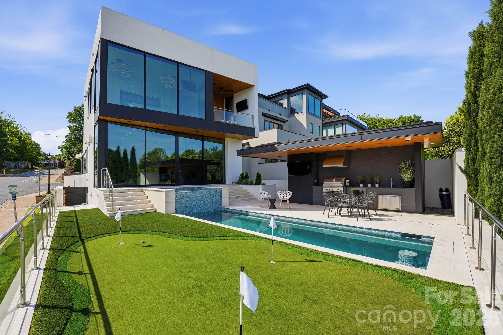 This exceptional modern residence blends steel and glass to create a striking architectural statement, offering arguably the best breathtaking Charlotte skyline views through dramatic floor-to-ceiling windows and three expansive patios. Designed for seamless indoor-outdoor living, the home features a one-foot-thick concrete wall, custom wood elements, and curated high-end finishes throughout. The open-concept layout includes a chef’s kitchen with integrated appliances, and walk-in pantry with pellet ice maker and refrigerator drawers, under counter and toe kick lighting while multiple living and entertaining spaces are wrapped in glass to maximize light and views. The primary suite showcases three walls of floor-to-ceiling glass, a private balcony, custom his and hers closets, and a spa-inspired bath with soaking tub, fireplace, and oversized shower. Additional highlights include a Savant smart home system, solar panels, guest suite, lower-level private bedrooms with en-suites, and a versatile upper-level entertainment space. Outdoor living is elevated with a resort-style pool featuring built-in seating, full outdoor kitchen, cabana bath, and custom putting green—all designed to capture year-round city views. Please see the attached features list for even more features. Agent is owner.