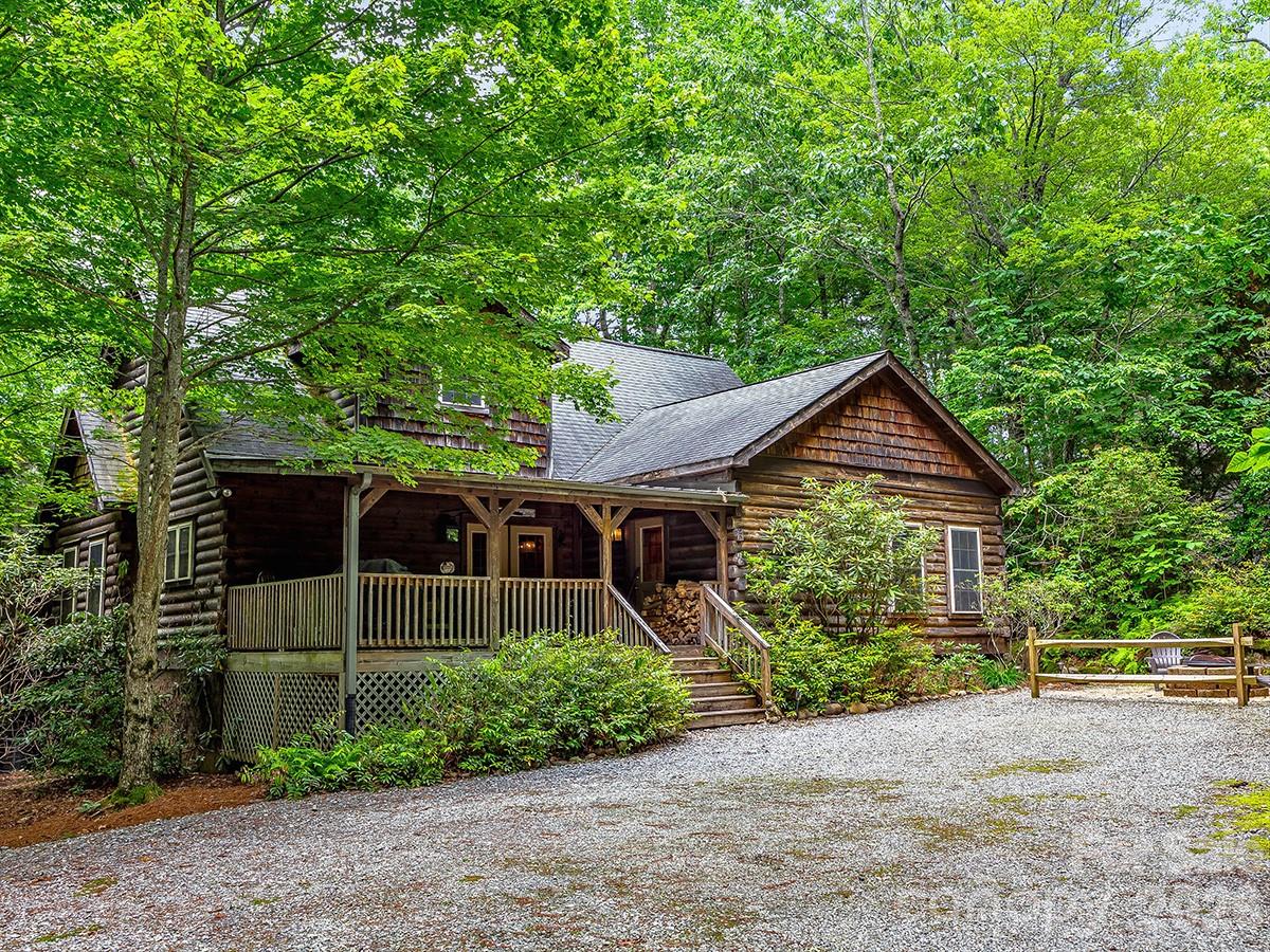 Nestled among the trees in the desirable Lake Toxaway area, Sweet Laurel Lodge is a beautifully maintained four-bedroom, four-bath mountain retreat offering privacy, comfort, and timeless mountain charm. Warm wood interiors create a welcoming atmosphere, while the spacious living room is anchored by a striking stacked-stone fireplace and dramatic floor-to-ceiling windows that bring the outdoors in.
The well-appointed kitchen flows seamlessly into the dining area, making it ideal for both everyday living and entertaining. Three of the four bedrooms feature private en-suite baths, providing comfort and flexibility for family and guests.
Step outside to the expansive deck and enjoy peaceful wooded surroundings, outdoor dining, and the serenity of mountain living. With glimpses of the nearby golf course and convenient access to the Lake Toxaway Country Club and marina, this home offers the perfect blend of seclusion and convenience. Membership to the club is available, subject to approval and availability.