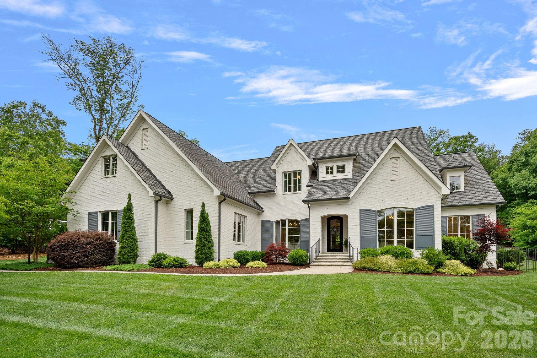Situated on a picturesque 1.47-acre lot in Carmel Acres, this stunning custom-built home blends quality craftsmanship and timeless architecture with refined finishes and gracious living spaces. From the moment you enter, thoughtfully designed spaces unfold, capturing the home’s true elegance. At the heart of the home, a beautifully appointed chef’s kitchen opens to the family room and features Calcutta Gold marble countertops and backsplash, Wolf range, Sub-Zero refrigerator, Bosch dishwasher, a generous center island, and a bright, sunlit breakfast nook. The spacious family room centers around an elegant gas fireplace and surround, a stunning chandelier, custom shelving flanking the fireplace and French Doors that open to the covered rear porch – perfect for seamless indoor-outdoor living. The main level primary suite offers peaceful backyard views and a spa-like bath with beautiful cabinetry, a large walk-in shower, soaking tub and an expansive closet. A charming guest suite is also on the main level and is showcased by decorative wallpaper and paneled wall accents, a walk-in closet and a shared bath connecting to the front playroom/bedroom. The upper-level features generously sized secondary bedrooms, an office, a playroom, bonus room with en-suite bath, and fabulous walk-in attic storage areas. The fully fenced backyard offers an ideal setting for a future pool and features an impressive custom-built playhouse with deck areas – a wonderful retreat for outdoor play and enjoyment (The playhouse is not heated or cooled.). Convenient proximity to Southpark, Ballantyne, Stonecrest and I-485. A rare offering that embodies timeless appeal, thoughtful craftsmanship and elevated everyday living – a truly special home!