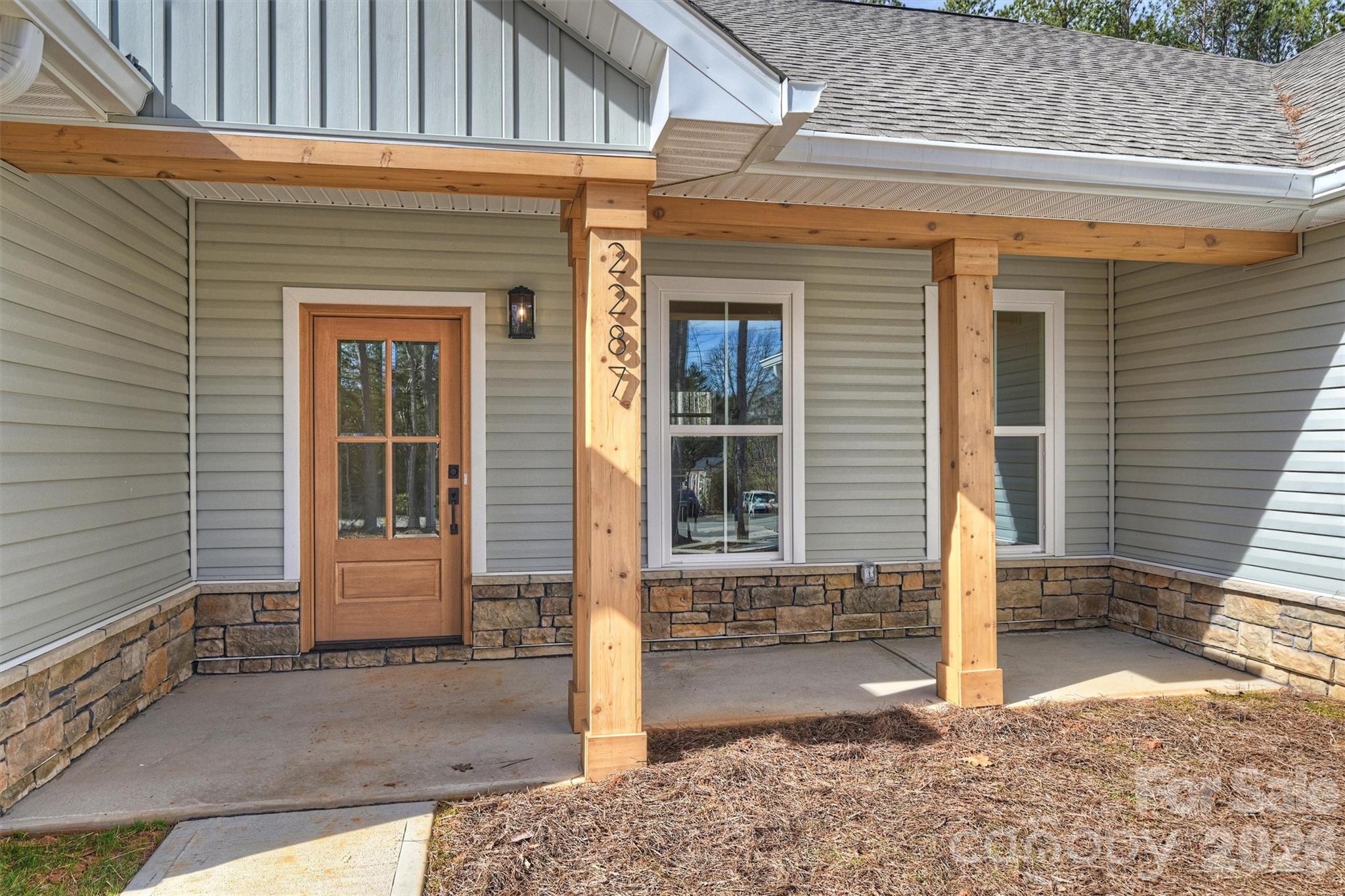 Recently completed and now available with NO HOA, discover North Pines—Lincolnton’s newest collection of thoughtfully crafted single-level homes by Brancer Homes. Located at 2287 Lee Lawing Road, this home blends elevated finishes with the natural privacy of tree-lined surroundings—all just 15 minutes from downtown Lincolnton and convenient to shopping in Sherrills Ford and Denver.

The exterior welcomes you with signature stone accents and stained wood front-porch columns, creating classic curb appeal with a warm farmhouse touch. Inside, the builder’s Modern Farmhouse Designer Package features clean lines, curated lighting selections, stylish cabinetry finishes, and quartz countertops throughout—bringing a fresh yet timeless aesthetic to every space.

The open-concept kitchen offers a spacious island with pendant lighting and flows seamlessly into the vaulted main living area, creating an airy and inviting environment ideal for both everyday living and entertaining. The primary suite is thoughtfully designed with a beautifully tiled shower wall and designer finishes that blend farmhouse character with modern convenience.

Additional highlights include a well-appointed laundry room with cabinetry and quartz counters, added recessed lighting, and designer neutral paint selections with crisp white ceilings. An extended two-car garage with exterior exit door, along with additional driveway parking, enhances everyday functionality.

Now that construction is complete, this home is part of a newly released collection in North Pines—offering a rare opportunity to own move-in ready new construction with elevated design, no HOA, and a peaceful rural setting in one of Lincolnton’s fastest-growing areas.