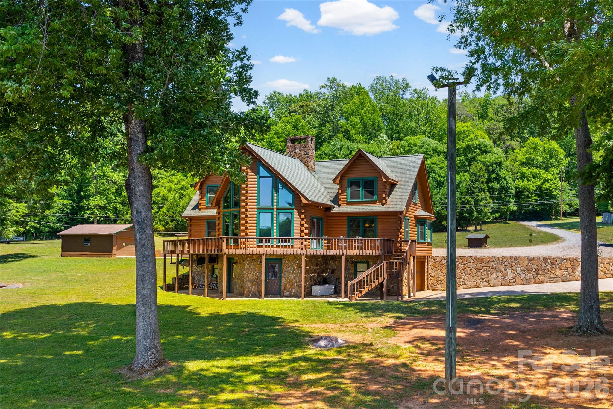 Waterfront Log Home on Lake Wylie. Spanning two acres with over 250 feet of pristine shoreline, including a private beach area. Magnificent water views are enjoyed from every room. The interior features solid wood doors, attractive lapped pine paneling, and continuous hardwood and tile flooring. The stunning two-story, A-frame great room is the focal point, centered by a massive stone fireplace with a rounded raised hearth and wood mantle. The gourmet kitchen is equipped with ceiling-height cabinetry, stainless steel appliances including a seamless five-burner range, and a pull-out pantry. The spacious primary bedroom suite is conveniently located on the main level and includes a walk-in closet and private bath. The main level also offers a large laundry room with a sink and a full bath with a jetted tub. The upper level has been newly renovated with a stacked stone chimney, new pine flooring, and two additional bedrooms featuring recessed lighting and ceiling fans. A renovated full bath with a large vanity and tile shower, plus a seasonal closet, completes this floor. The expansive unfinished basement includes a full bathroom and a garage bay. The property boasts six total covered parking spaces across a detached three-car garage with new insulated doors and epoxy flooring, a two-car carport, and an additional detached two-car garage. Waterfront amenities are established for immediate enjoyment, including a pier, a covered dock with a swing, a floating dock, and a boat lift. The sale includes the home lot at 3805 Marwick Road and the adjoining one-acre lot at 3814 Cane Court. (Note: Please use caution on the top dock deck, as the boards are deteriorating.)