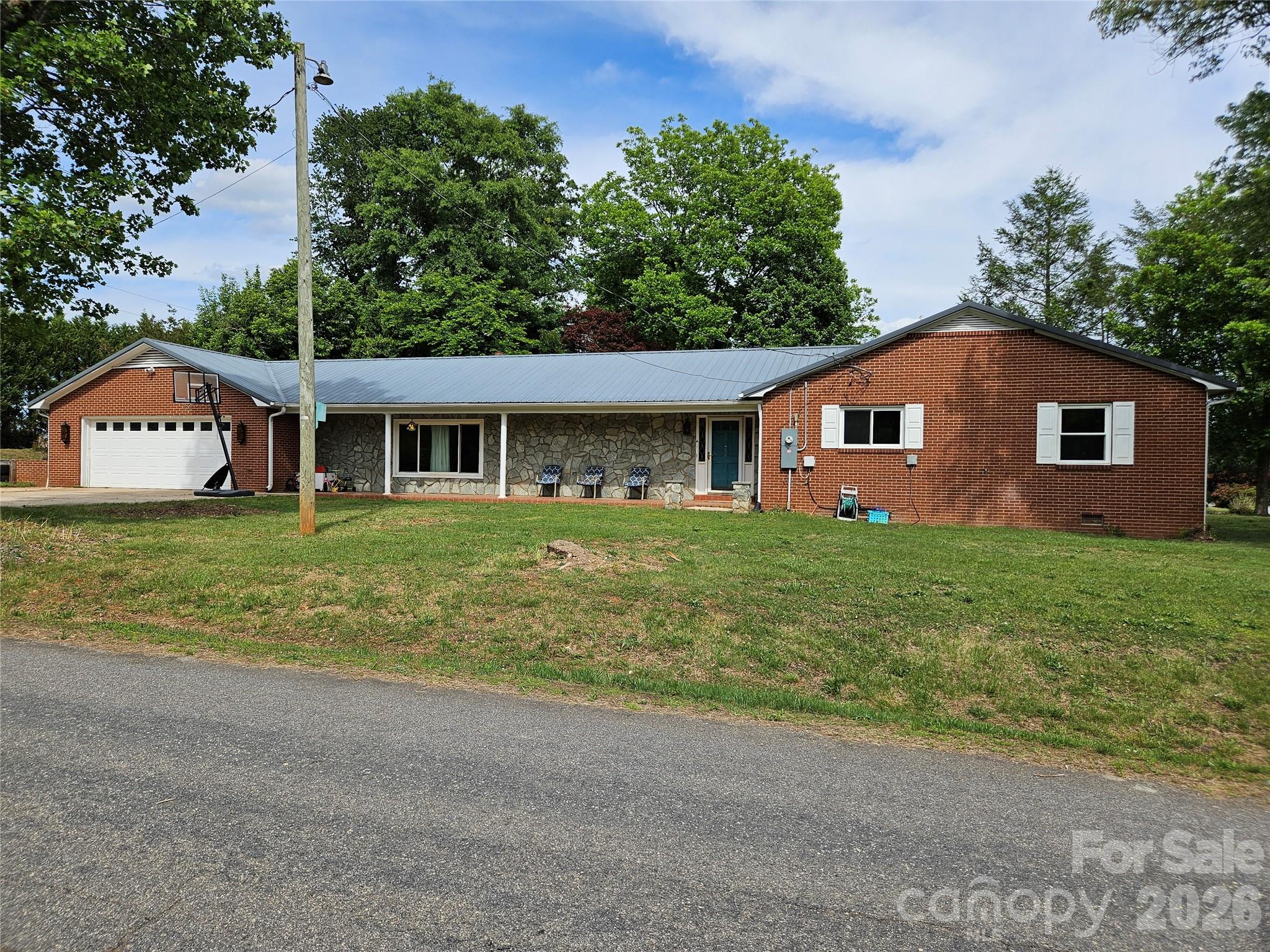 Reduced again, now only $319,900. Beautiful all one-level brick home in Granite Falls offering comfort, character, and updates throughout! Situated on an almost half-acre corner lot at Sherrill Dr. and Kaley Ln just outside the town limits, no city taxes.  This 3 bedroom, 2 bathroom home features a welcoming rocking chair front porch and an inviting layout designed for everyday living and entertaining.

Step inside the foyer accented with charming brick walls and coat closet storage before entering the HUGE family room showcasing laminate wood flooring, a beautiful stone fireplace with gas logs, and rustic wood-style beamed ceilings. The spacious kitchen offers a gas range, refrigerator, stainless single-basin sink, tile backsplash, faux granite countertops, pantry storage, and excellent functionality. The original living room is currently being utilized as a large dining area, providing flexible living and dining space to fit your needs.

The primary bedroom features a stylish wood accent wall, while all bedrooms include ceiling fans for added comfort. The guest bathroom offers a double vanity, walk-in shower, laundry area, and convenient walk-in closet nearby. The second bath features unique rustic finishes with metal wall accents.

Enjoy outdoor living on the expansive rear patio — perfect for grilling, relaxing, or entertaining guests. Additional highlights include an oversized garage, ample parking. 2008 metal roof.  Updates since 2021 include vinyl replacement windows, new electrical panel, gas logs, and a 2021 dual-fuel propane/electric HVAC system.

Conveniently located near shopping, dining, schools, and commuter routes, this move-in ready Granite Falls home offers space, charm, and value all on one level!