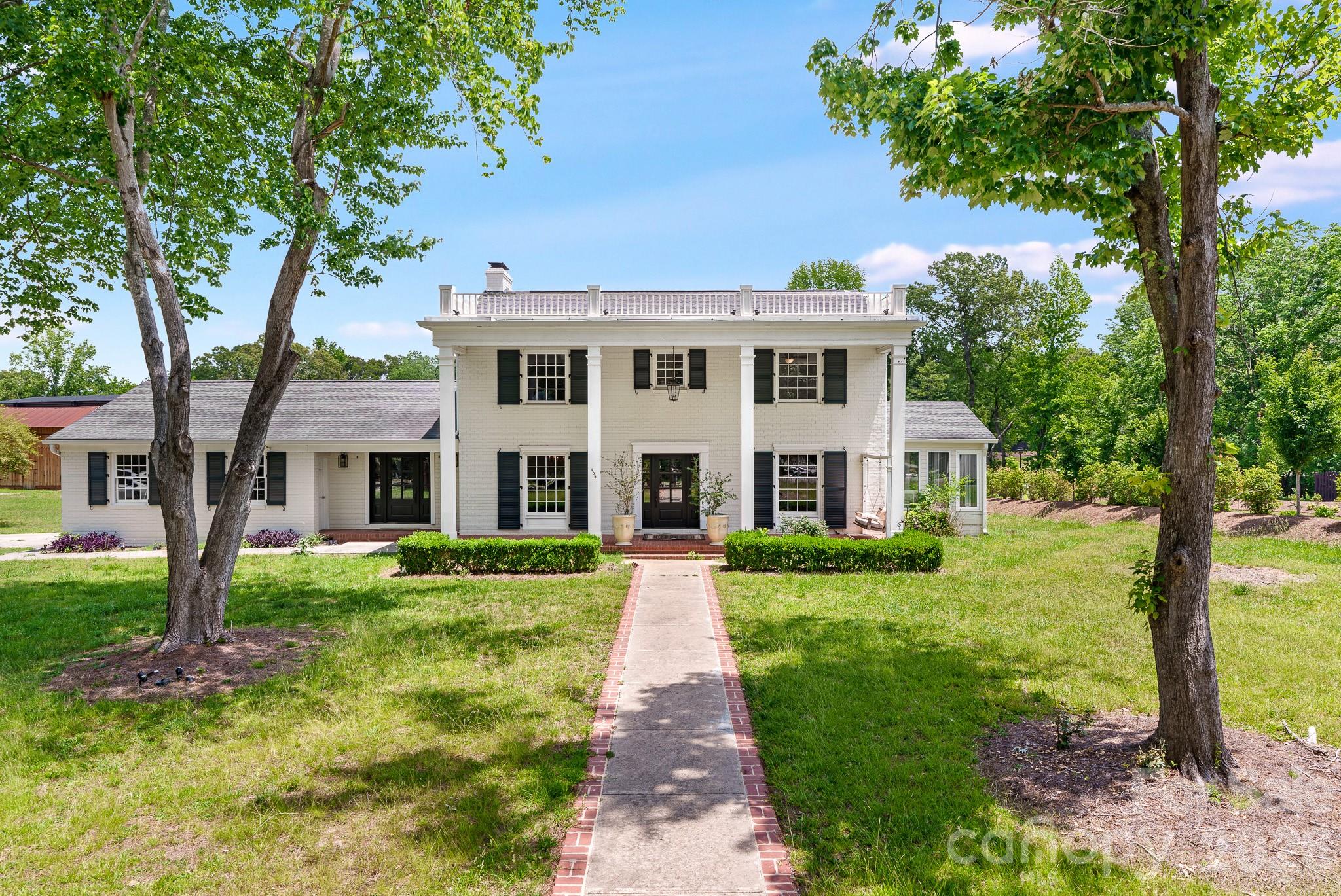 Rare opportunity in Downtown Waxhaw! This 1960 full-brick, two-story Colonial sits on a sprawling, picturesque 1.2+ acre lot, offering an unmatched combination of privacy and walkable village convenience. Boasting 4 spacious bedrooms and 3 full bathrooms, this home is filled with old-world architectural charm and timeless character just waiting to be revived.The main level features a formal living room, dedicated dining room, kitchen, and a cozy den anchored by a stunning, statement-piece fireplace. Enjoy peaceful views of your massive backyard from the bright, airy sunroom. Outside, parking is a breeze with a 2-car attached garage plus an expansive driveway offering 8+ additional parking spaces—perfect for hosting guests or storing recreational vehicles.While the home needs some TLC, its solid brick construction, exceptional floor plan, and premier downtown location offer infinite potential. Bring your imagination and vision to transform this estate into a true Southern showstopper! Selling AS-IS.