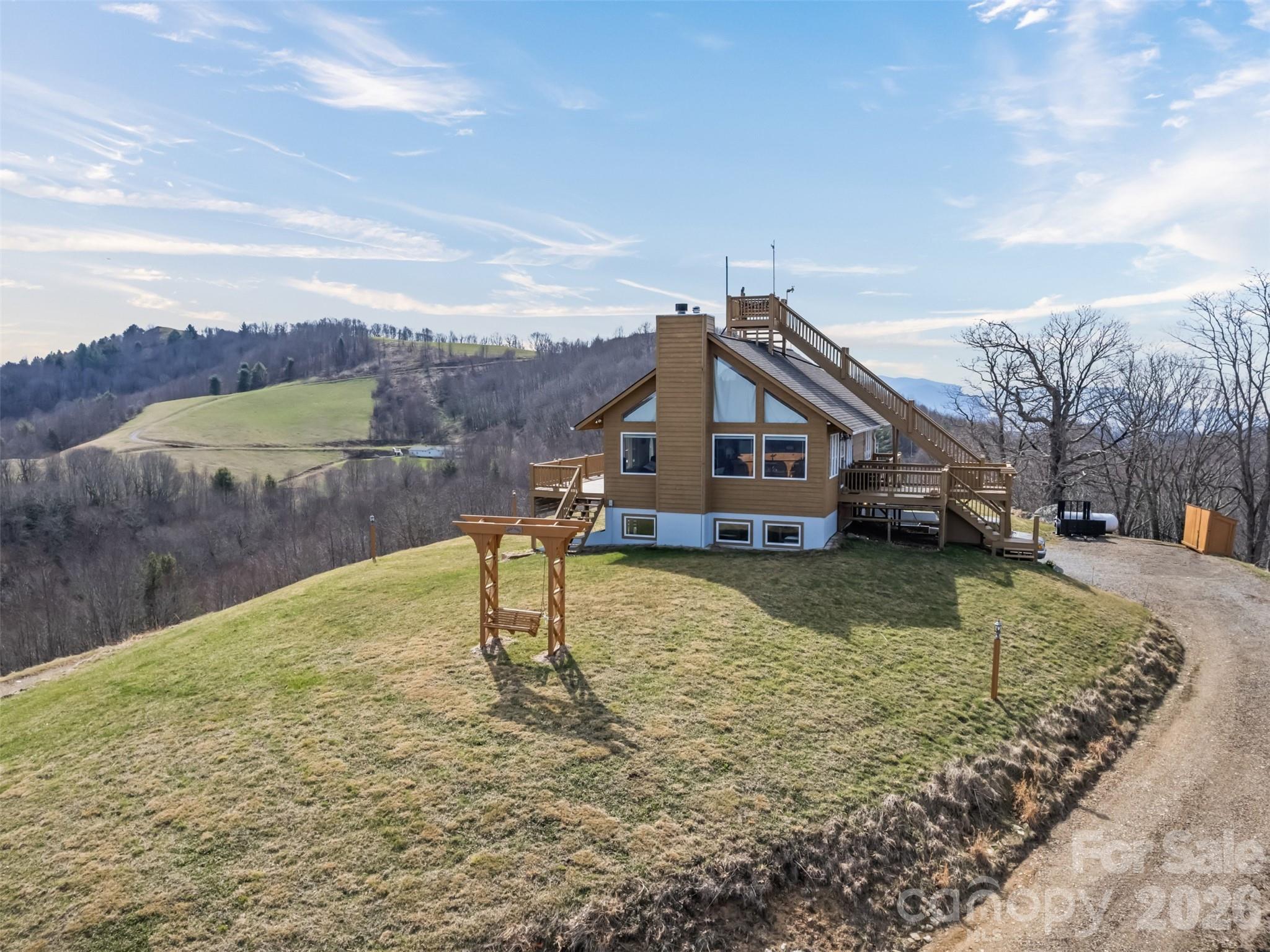 Stunning long-range views in every direction make this 30-acre mountain retreat feel like you’re on top of the world. Indescribable sunrises and sunsets. Mostly cleared and gently rolling, the property offers two additional excellent home sites, providing exceptional flexibility for expansion, guest homes, or investment opportunities. Elevations range from 4,100 to 4,500 feet, delivering cool mountain breezes, peaceful privacy, and abundant wildlife—where hawks soar and nature surrounds you. ***The impeccably maintained main home features recently painted cedar siding and a 2025 roof, blending mountain charm with thoughtful updates. Inside, the main-level living area centers around a dramatic two-story great room with walls of windows, hardwood floors, and a stone-faced wood-burning fireplace. The open kitchen includes an island, breakfast bar, and dining area—perfect for entertaining while enjoying the breathtaking views. The main level also offers two bedrooms, two baths, and laundry, making everyday living convenient and comfortable. ***Step outside onto the wraparound deck or climb to the unique crow’s nest landing for even more spectacular scenery and perfectly private silence. This home truly brings the outdoors in, with views from nearly every room. ***The lower level features a private apartment with both interior and exterior entrances, kitchenette, and Quadra-Fire wood stove, ideal for guests, or multi-generational living. Additional features include: all furniture, a 26-foot-long one-car garage with space for a vehicle and mower, attic access with steps and lighting for extra storage, and propane lines already in place for the range and fireplace, with an owned 500-gallon propane tank. HOA: road maintenance only as needed ($100 in 2025).