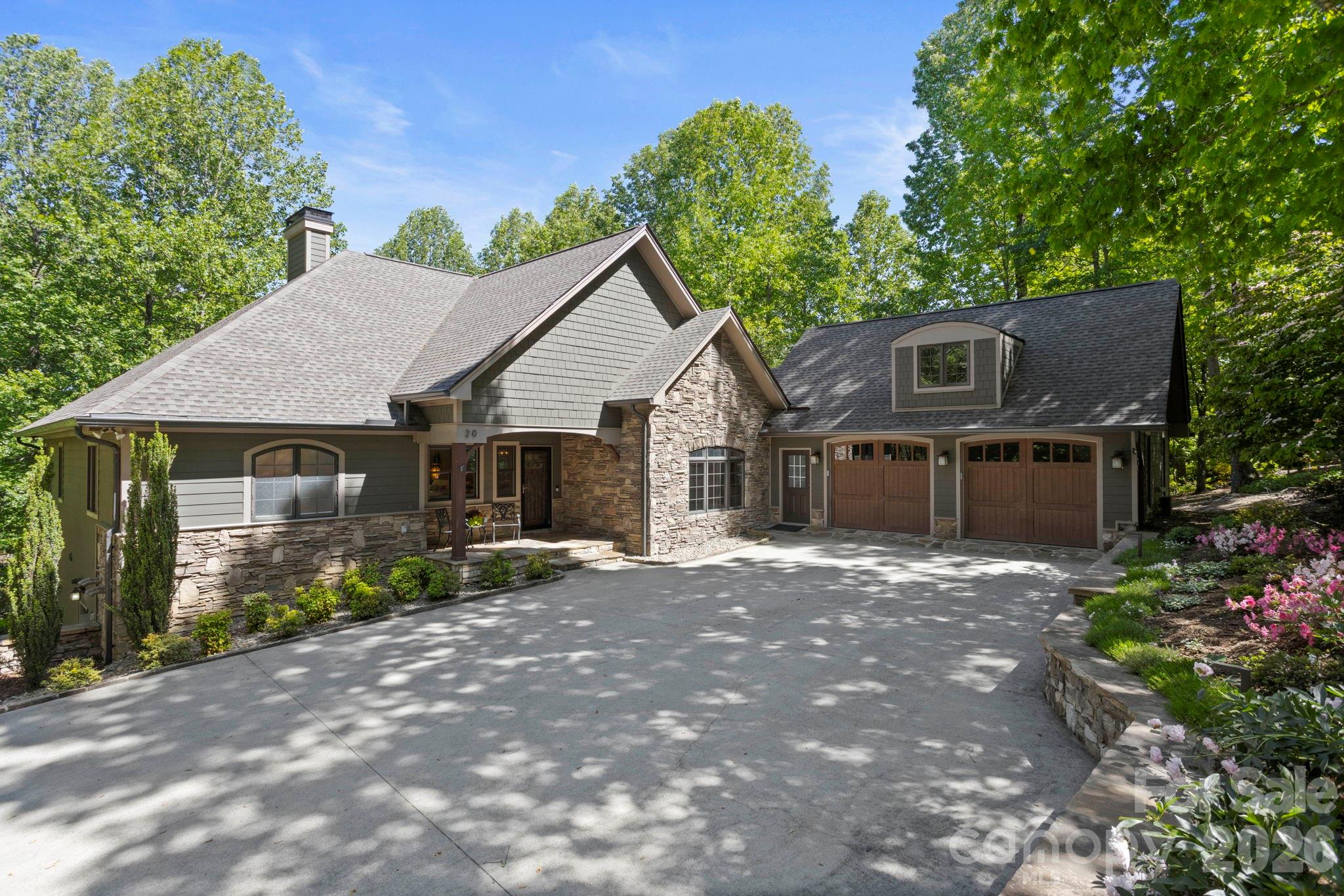 Experience the epitome of luxury living with uncompromising quality, high-end finishes, designer lighting, and exquisite attention to detail throughout this extraordinary residence located in coveted Kenmure - a prestigious gated golf course community. Perfectly situated on 1.25 acres in a breathtaking park-like setting on a quiet cul-de-sac, this architectural masterpiece offers the utmost privacy surrounded by gorgeous natural beauty. Prepare to be impressed as you traverse the level driveway lined with stunning stone retaining walls and professionally designed landscaping. Upon entering you are immediately captivated by high ceilings, walls of windows flooding the home with natural light and impeccable craftsmanship defining every corner of this exquisite home. The main level boasts gleaming hardwood floors throughout and a flowing open floor plan ideal for entertaining family and friends. The spectacular great room features a vaulted ceiling, dramatic stone fireplace with gas logs, custom built-ins with illuminated glass shelving and an art display niche creating a warm yet sophisticated gathering space. The great room flows seamlessly into the chic dining area accented by stunning designer lighting, a professional gourmet kitchen, and an inviting bar area. Designed to impress even the most discerning chef, the gourmet kitchen showcases quartzite countertops, tile backsplash, farmhouse sink and premium stainless appliances including a Fisher & Paykel wall oven with warming drawer, wall microwave, gas cooktop with exhaust hood, double drawer dishwasher and refrigerator/freezer. A spacious breakfast bar and pantry closet complete this exceptional culinary space. The sophisticated bar area surrounded by walls of windows perfectly captures the serene natural setting and is ideal for entertaining guests. Features include quartzite countertops, custom cabinetry, wine refrigerator and beverage refrigerator. The expansive luxurious primary suite serves as a private retreat featuring two walk-in closets and a spa-inspired bath with quartzite double  vanities with designer lighting, center island with drawers, freestanding Jacuzzi soaking tub, stunning walk-in tiled shower with bench, linen closet, and private water closet. Additional main level highlights include a beautifully appointed study with wall of windows, an elegant powder bath with unique designer sink and a well-equipped spacious laundry room featuring abundant cabinetry, leathered granite countertops, laundry sink, walk-in pantry, and additional storage closet. A striking custom staircase with designer iron railings leads to the exceptional lower level featuring a spacious family room with tray ceiling, additional flex/sitting area, stone gas fireplace with hearth flanked by custom built-ins and sliders opening to the covered deck. Two generous guest suites and two full guest baths with walk-in showers -one being en suite - provide ideal accommodations for family and guests. The lower level also offers two enormous storage areas. Experience the ultimate in luxury mountain living while relaxing on the covered flagstone front porch, expansive covered main-level deck perfect for al fresco dining and entertaining or the private lower-level outdoor covered deck. Additional features include a generator, radon mitigation system, in-home water filtration system, oversized epoxy-floored two-car garage with built-in cabinetry and storage, plus dedicated space for a golf cart. Ideally located just minutes from The Village of Flat Rock, historic downtown Hendersonville, fine dining, shopping, and local amenities, this spectacular residence truly offers luxury as a lifestyle. Simply stunning and an absolute must-see!