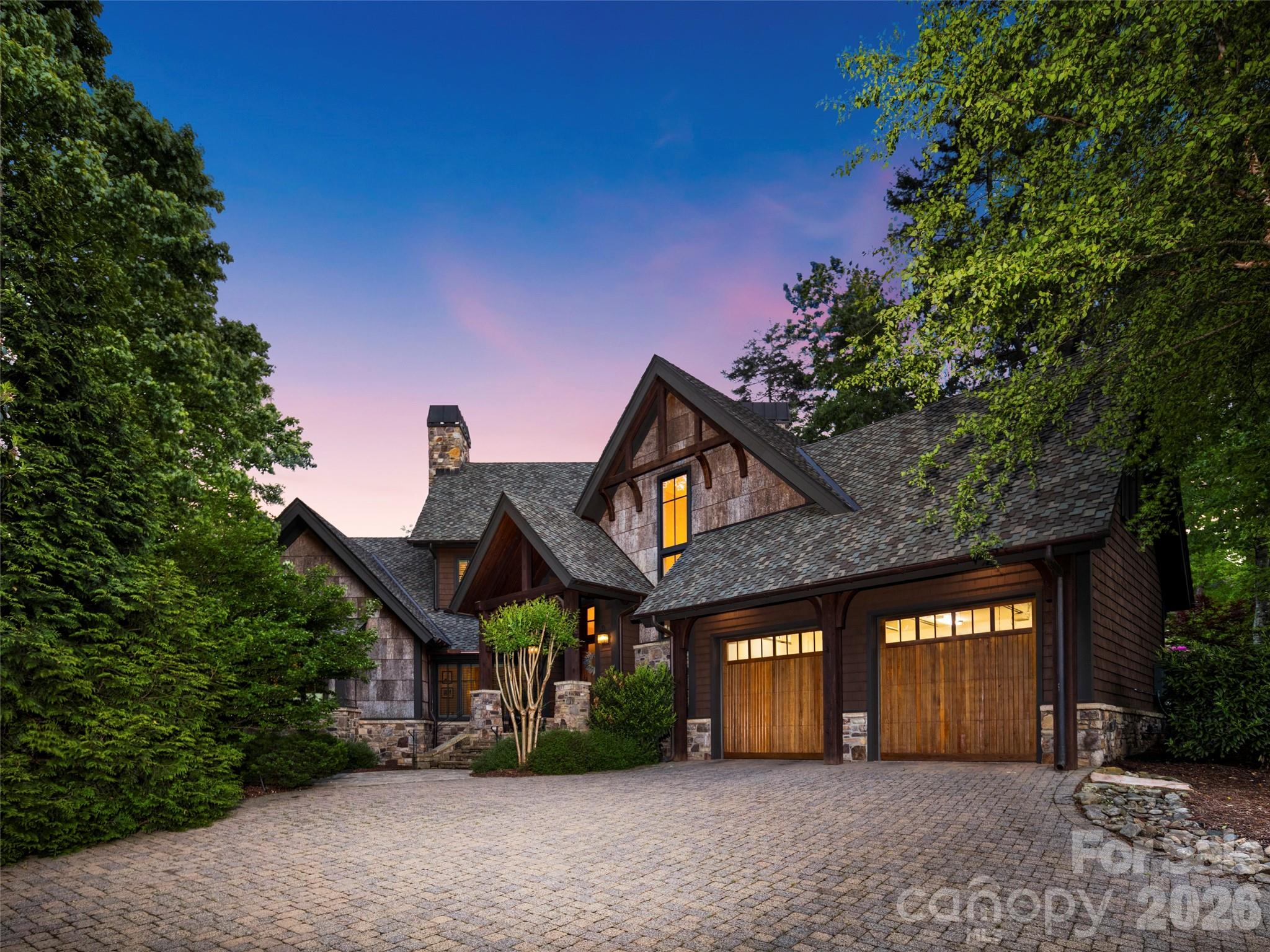 Nestled within the gates of The Cliffs at Walnut Cove, this masterfully crafted mountain estate offers an unparalleled lifestyle of rustic elegance and refined comfort. The residence immediately impresses with its striking architectural silhouette, featuring a harmonious blend of heavy timber, stone, cedar shakes and natural tree bark siding that mirror the natural splendor of its Arden, North Carolina surroundings. Upon entering, the expansive great room serves as a breathtaking centerpiece, defined by soaring wood vaulted ceilings anchored by massive exposed beams and a floor-to-ceiling stone fireplace that commands attention. Walls of oversized windows frame tranquil views of the lush landscape from every room while bathing the interiors in soft, natural light. This seamless integration of the outdoors continues into the gourmet kitchen - a chef’s sanctuary outfitted with furniture-grade cabinetry, three copper sinks, sprawling granite countertops, and professional-grade appliances. A dedicated beverage center and a large central island make this space as functional for intimate morning coffee as it is for grand-scale entertaining. The oversize primary suite is a private retreat designed for ultimate relaxation, offering its own stacked-stone fireplace, wood vaulted ceiling and direct access to the expansive and private outdoor spaces. Throughout the home, the attention to detail is evident, from the rich hardwood flooring to the custom built-ins and exquisite millwork. The property’s outdoor living areas are truly extraordinary, designed to take full advantage of the community's high-altitude privacy. A massive enclosed sunroom provides a year-round sanctuary, complete with a rugged stone fireplace, a handcrafted custom built bar from locally sourced live edge black walnut, and ample space for lounging or gaming. A wall of sliding doors opens to the meticulously landscaped private grounds featuring a tiered lighted stone waterfall and pond, creating a rhythmic soundtrack for evenings spent around the large custom built-in stone fire pit. The back wall of the sunroom opens onto a large patio with a motorized retractable sun/rain awning, and a custom cabinet enclosed refrigerator and ice maker, perfect for outdoor dining rain or shine.  A Kohler generator and Starlink satellite ensure uninterrupted comfortable living. The second floor offers two guest bedrooms each with full bathrooms and ample closets, as well as an office/third guestroom with a full bathroom and walk out attic storage. The office has a custom built black walnut desk and cabinetry. A new roof was installed in 2025 and many mechanicals have been updated including new HVAC units  in 2023 and 2021, a new Navien tankless water heater installed in 2026 and a Kohler generator installed in 2026.  The LG washer/dryer installed in 2026 convey with the house. Membership at The Cliffs at Walnut Cove grants access to world-class amenities including a Jack Nicklaus Signature golf course, a sprawling state-of-the-art Wellness Center with indoor and outdoor pools, and the social heartbeat of the community, "The Tavern." Located just minutes from the Blue Ridge Parkway and the vibrant cultural scene of Asheville, this estate represents the pinnacle of luxury living in the Blue Ridge Mountains. An adjoining lot is available for purchase but not included in the price.