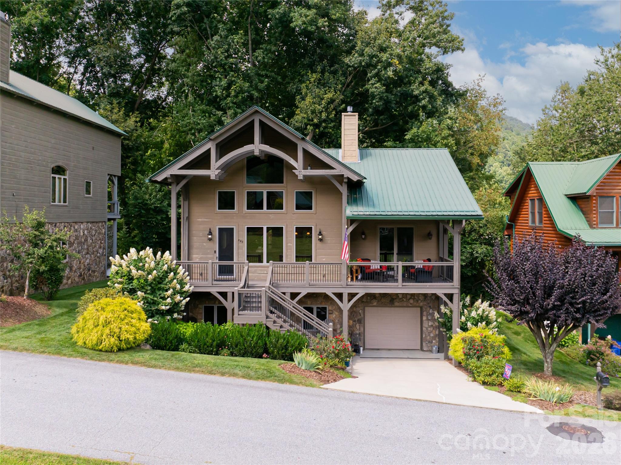 Tucked within the natural contours of Maggie Valley, 649 Panoramic Loop offers a more intimate expression of mountain living, where layered, close-range views rise just beyond the home, creating a sense of depth, texture, and year-round visual interest. Set in a peaceful valley setting, the property feels both protected and connected to its surroundings, with the mountains unfolding in soft, overlapping ridgelines from the front of the home.

The interior is anchored by a striking great room, where soaring timber beams, expansive windows, and a floor-to-ceiling stone fireplace establish a warm yet refined gathering space. Natural light fills the home throughout the day, highlighting rich hardwood floors and thoughtfully selected finishes. The open-concept design transitions seamlessly into a well-appointed kitchen featuring granite countertops, stainless steel appliances, a central island, and generous storage, equally suited for entertaining or everyday living.

The main-level primary suite offers comfort and privacy, complete with a spa-inspired bath, walk-in closet, and direct access to outdoor living. Upstairs, a guest bedroom, full bath, and flexible loft provide additional space for work or relaxation. The lower level extends the home’s functionality with a secondary living area, additional bedroom, and versatile space for guests or recreation.

Outdoor living is thoughtfully designed to capture two distinct experiences. The expansive front deck is oriented toward the mountain views, offering a front-row seat to layered ridgelines and the ever-changing light across the valley. In contrast, the rear deck off the kitchen and dining area is tucked into a private, wooded setting, creating a quiet retreat surrounded by nature. Wildlife is a regular part of the experience, with elk frequently passing through and grazing nearby, along with other native species that bring the landscape to life.

Located just minutes from Cataloochee Ski Area, the Blue Ridge Parkway, and the shops and dining of downtown Waynesville, this property offers both convenience and escape. The community allows for short-term rentals, offering flexibility for future use, while the current owners have enjoyed the home as a full-time residence.

649 Panoramic Loop presents a rare opportunity to experience a balanced mountain lifestyle, where view-oriented living, natural privacy, and everyday comfort come together in one of Western North Carolina’s most desirable settings.