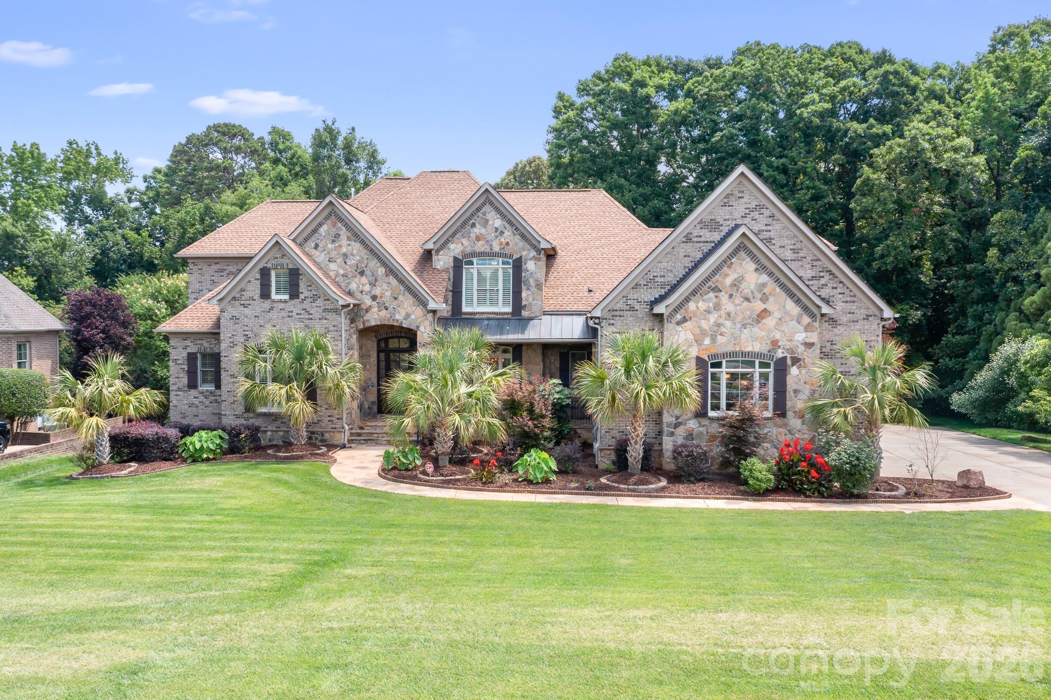 Located in the distinguished, gated Providence Downs neighborhood, this impressive home features over 7000 square feet of well appointed living space. Two story foyer upon arrival, formal office and dining rooms, two story living room with stone fireplace. The kitchen is well designed with two refrigerators, huge island with breakfast bar, dining area and ample counter/cabinet space. Keeping room open to the kitchen/dining and has a stone fireplace. First floor primary suite with fireplace, two custom closets and private balcony, overlooks pool and tree lined yard. Laundry rooms on first and second floors for convenience. Second primary bedroom on second level, three large additional bedrooms (one with private bath) and huge flex room. The basement can be used as a second living quarters. Full kitchen with granite counters, breakfast bar and dining area. Rec room/living room, bedroom and spa-style bath. The outdoor living area is as nice as the inside! Saltwater pool (installed 2019) with tanning ledge, waterfall feature and travertine deck surrounded by private fenced yard and lush landscape. Irrigation supplied by well. New solar panels in 2022, Four car, side load garage (1221 square feet!). Over 300 square feet of walk-in attic storage. Plantation shutters finish the home out nicely. Three water heaters and a new cooktop in 2026. There is no shortage of space in this well appointed home!