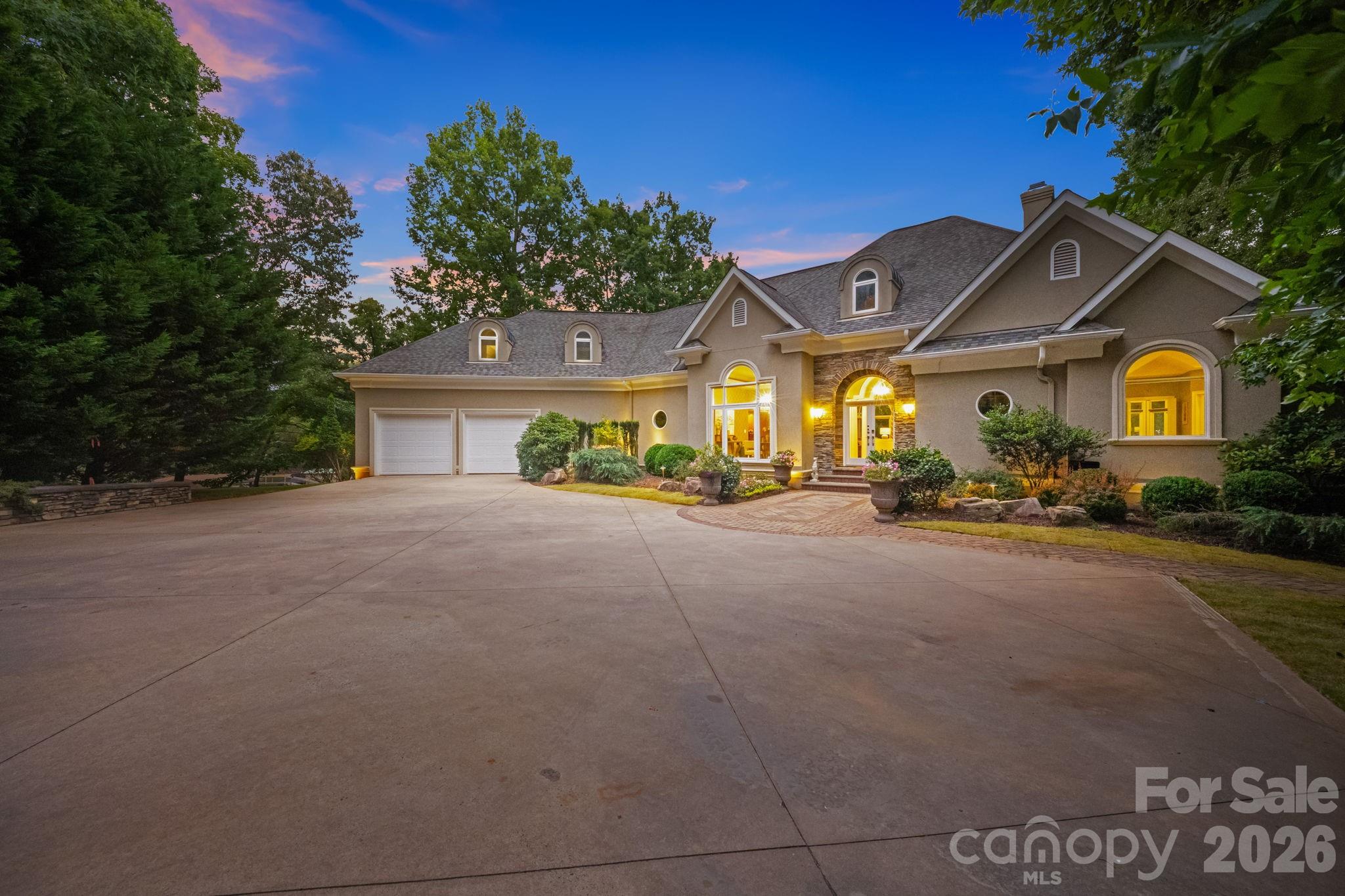 Luxury Waterfront Estate on Lake Wylie
Situated on one of the most desirable waterfront lots on Lake Wylie, this exceptional estate offers over 450 feet of flat, usable shoreline, breathtaking long-range water views, and a rare combination of privacy, luxury, and functionality. Located on a private road shared by only five homes, this remarkable property offers the peace and exclusivity of a private retreat while remaining just minutes from Charlotte, the airport, dining, shopping, and everyday conveniences. Located within the highly sought-after Fort Mill School District and featuring no HOA, this property presents a truly rare opportunity.
Waterfront & Grounds are one of the property's most extraordinary features is its over 450 feet of flat shoreline, deep-water access, and beach access, a combination rarely found on Lake Wylie. Enjoy boating, fishing, paddleboarding, kayaking, and swimming directly from your backyard while taking in panoramic lake views and unforgettable sunsets.
A private dock complete with a boat lift, floating dock, pier, and additional electrical service provides effortless access to the lake.
The grounds are beautifully landscaped with specimen plantings including Blue Atlas Cedars, Mugo Pines, Colorado Blue Spruce, Japanese Maples, and numerous ornamental trees and shrubs connected by stone walkways that complement the waterfront setting.
Main Residence is designed to maximize lake views, the home features dramatic floor-to-ceiling windows, soaring ceilings, extensive custom molding and trim, and water views from nearly every room. Natural light fills the home, creating a seamless connection between indoor and outdoor living.
The main level showcases a luxurious lakeside primary suite with a spa-inspired bath and dual custom walk-in closets with extensive built-ins. Formal dining spaces feature a stunning double tray ceiling with uplighting and designer fixtures.
At the heart of the home is a chef's kitchen appointed with custom Canadian maple cabinetry, premium appliances, an oversized island, wet bar, walk-in pantry, and a fully equipped scullery, designed for effortless entertaining. An additional main-level guest suite offers flexibility and privacy.
Upstairs, spacious guest suites offer abundant natural light, beautifully appointed baths, extensive storage, and a dedicated home theater with stadium seating.
An extraordinary detached 6-car garage and flex space is fully heated, cooled, insulated, and professionally soundproofed. Complete with a kitchen, bathroom, workshop, and flexible living areas, it is ideal for guests, a home business, collector vehicles, or the ultimate hobby retreat.
A workshop-style basement with a drive-out garage door provides additional storage and workspace.
A Rare Lake Wylie Offering, combining over 450 feet of shoreline, deep-water access, beach access, exceptional privacy, spectacular sunsets, top-rated Fort Mill schools, no HOA restrictions, and convenient access to Charlotte and the airport, this extraordinary waterfront estate represents one of the finest opportunities on Lake Wylie. A true waterfront compound designed for luxury living and unforgettable memories.