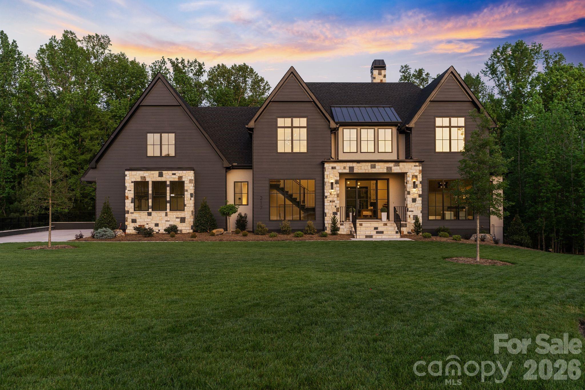 Set within the prestigious Cardinal Crest community in Weddington, this exceptional custom estate blends refined architecture with effortless livability across more than 6,500 square feet of thoughtfully designed space.

A striking first impression leads into a seamless main-level layout where natural light, wide-plank flooring, and curated finishes create a warm yet elevated aesthetic. The chef’s kitchen anchors the home with an oversized island, custom cabinetry, and a fully equipped scullery—designed for both everyday function and elevated entertaining. The adjoining living room opens completely to the covered terrace through expansive sliding doors, creating a true indoor-outdoor experience complete with a fireplace and serene wooded views.

The main-level primary suite is a private retreat, featuring a spa-inspired bath with dual vanities, soaking tub, and an oversized walk-in shower. Additional main-floor highlights include a dedicated office, dining space, mudroom, and laundry.

Upstairs, three spacious bedrooms with en-suite baths are complemented by a recreation room, bonus room, and an additional office—offering flexibility for work, wellness, or play.

The fully finished basement is crafted for unforgettable entertaining, featuring a spacious family room, media room, guest bedroom, and full bath, along with a custom bar and a stunning glass-enclosed wine vault. With direct access to the backyard patio and pool, this level seamlessly extends the home’s living space.

Designed to rival a private resort, the backyard showcases a beautifully planned pool and spa, creating the ultimate setting for relaxation and entertaining. Framed by lush landscaping and peaceful surroundings, this outdoor retreat perfectly complements the home’s indoor-outdoor lifestyle.

Every detail has been carefully considered, from the designer lighting and custom millwork to the seamless flow between indoor and outdoor living spaces. Situated on a private homesite in one of Weddington’s most desirable communities, this home offers a rare combination of luxury, functionality, and modern design.

Just minutes from I-485, top-rated schools, dining, and shopping, Cardinal Crest delivers the ideal balance of tranquility and convenience.