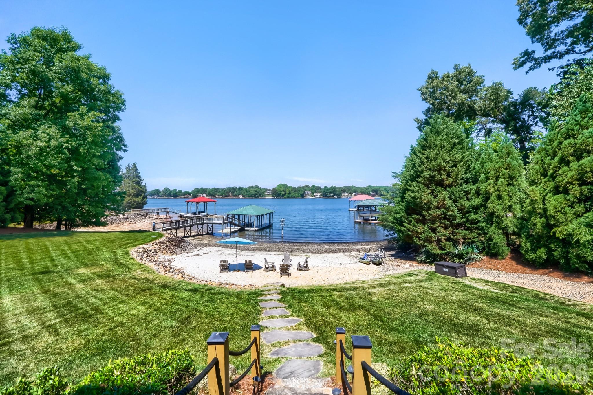 Take in incredible sunset views from this waterfront escape that blends contemporary coastal style with touches of industrial design. Designed for both comfort and entertaining, this home offers spacious gathering areas and room for family and guests to enjoy relaxed lakefront living. Fresh exterior paint adds to the home’s appeal and highlights its beautiful waterfront setting. The main house features a primary bedroom on the main level and three additional bedrooms, each with an ensuite bathroom in the stunning walk out basement. One of these is a distinctive custom bunk room that creates a fun and flexible space for hosting family and friends.  The three-car garage features a private apartment above, ideal for multigenerational living, extended guest stays or short term rentals. Outside, the property is equally impressive with a screened porch perfect for soaking in lake views, a private covered dock, an expansive lawn, a large deck connecting the main house and apartment, a fenced pet area, a lakeside fire pit, a large natural sandy beach and boat launch that completes the ultimate waterfront lifestyle. Previously used as a vacation rental, this property has demonstrated strong income potential. To make the transition effortless, furnishings are included, offering a move-in-ready waterfront getaway or investment opportunity. Lake views from most every room in the main house.