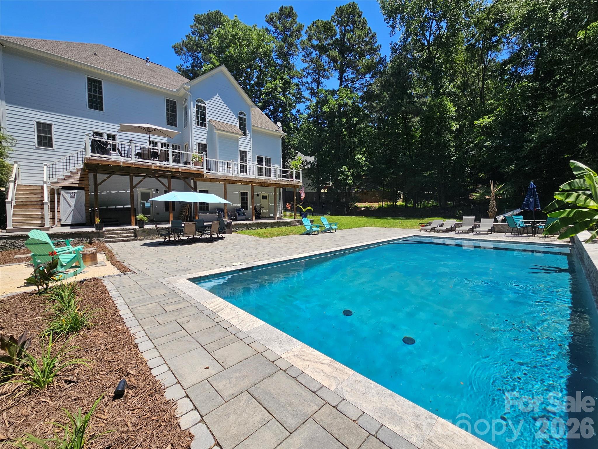 Welcome Home to this beautifully updated 5-bedroom, 4.5-bath home on a peaceful cul-de-sac lot. This well-maintained home on the Tega Cay peninsula offers everything with no HOA restrictions and award-winning Fort Mill Schools. From the inviting front porch, step inside the grand two-story foyer. The main level features a large office with built in desks and cabinets and a spacious dining room. The remodeled kitchen is a chef’s dream, complete with double ovens, ample counter space and a large open layout perfect for cooking and entertaining. Anchored by a spacious breakfast bar, the kitchen flows effortlessly into the breakfast area and the two-story family room which impresses with soaring ceilings, abundant natural light and a cozy gas fireplace. The main level also includes the laundry room and a bedroom ideal for visitors or extended family. Upstairs, the primary suite offers a tray ceiling and spa-like ensuite which features a frameless glass shower, dual vanities, and a soaking tub. Two additional bedrooms share a Jack-and-Jill bath, and the upper level is completed by a 4th bedroom/bonus room. The finished walk-out basement could function as a secondary living space with a flex room, full bathroom, abundant storage, and large utility room with laundry hook ups. A full kitchen with bar seating features a gas stove, wine fridge and beer taps! The built-in sauna and an impressive fully set-up theater room make the perfect retreat for fun or relaxation! It’s the perfect setup for multigenerational living, guests or unforgettable entertainment. Outdoors, escape to your own private resort-style backyard ideal for entertaining or relaxing. You’ll find a heated saltwater pool with tranquil waterfalls and tanning ledge, relaxing hot tub, outdoor bathroom, expansive paver patio, deck, porch, sand fire pit area and surrounding green space all on a large 1/2 acre lot. This home is truly move-in ready. The location is unbeatable, only minutes from shopping, restaurants, hospitals, schools, and major highways. Tega Cay offers endless recreational amenities including golf, tennis, pickleball, and lake access. This home is just a short commute to Charlotte, Rock Hill, Ballantyne & more! Don't miss your chance to own this home!