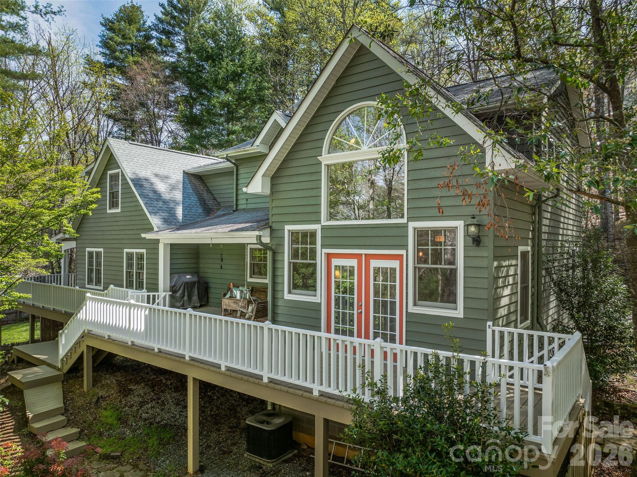 Tucked away on 2 private, wooded acres in Fairview, this custom home offers privacy, nature, and character—just 20 minutes from downtown Asheville’s restaurants, music, and arts. The surrounding area features organic farm stores, roadside produce and flower stands, as well as local craft breweries. The main level includes the primary bedroom, vaulted ceilings, and a cozy fireplace that anchors the living space. Upstairs, a loft adds charm and versatility, while a dedicated home office provides room to work in peace on the lowest level. A wraparound deck and covered porch invite you to enjoy the mountain air, while the fenced yard is perfect for pets. The layout offers an artful balance of airy gathering spaces and quiet corners, designed for both connection and solitude. With nearby hiking trails and room to breathe, this is refined mountain living for those who value beauty, privacy, and a sense of place.