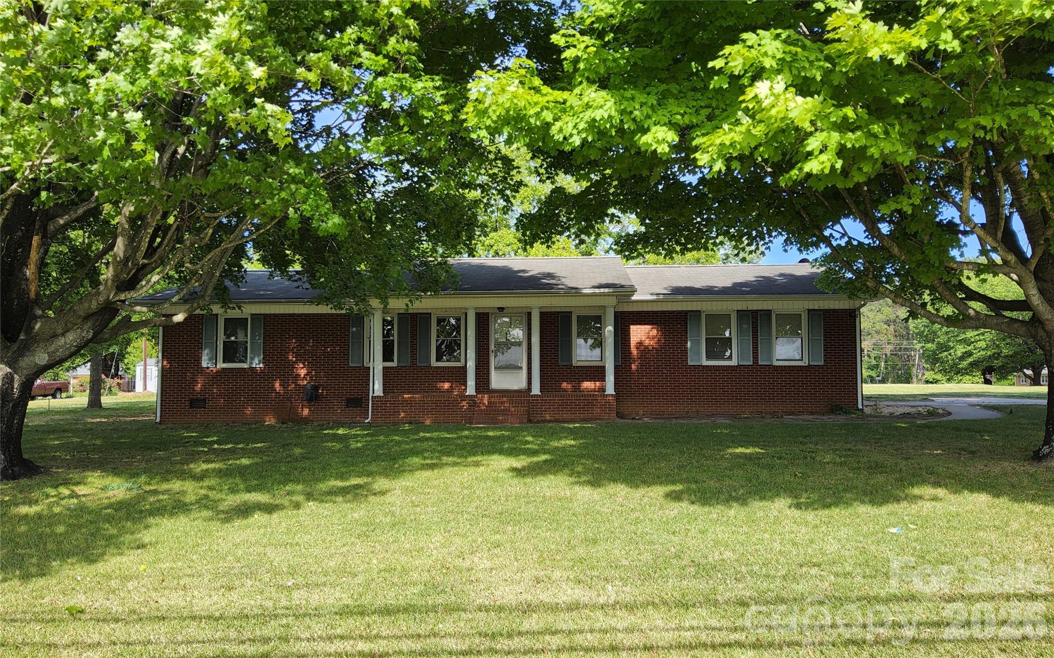 BRICK RANCH IN IDEAL LOCATION.  This home is situated on a perfectly level, grassy lot of .71 acres just outside city limits.  Easy drive to Town for shopping, restaurants, medical facilities, etc.   Carport is attached for convenience and lot is shaded by majestic oak trees. Home is roomy and has great potential for you to upgrade to your heart's desire.  Level lot provides great space for gardening, installing play gyms and even fencing for your pet's safety.    Recent upgrade to property is a new heat pump.  This location is in the region called the ISOTHERMAL BELT and is a zone in western NC foothills with milder temperatures contributing to longer growing seasons than in the immediate surrounding regions.  This phenomenon usually occurs on the southern slopes of mountains and foothills protected from frost and freezing temperatures by higher mountains to the North and Northwest.  Enjoy summertime outdoor activities close by such as hiking, golfing, swimming, kayaking, horse-back riding and zip-lining.  The Tryon International Equestrian Center is a short drive, for the equine enthusiasts.  Ideal location for a fulltime or vacation home.