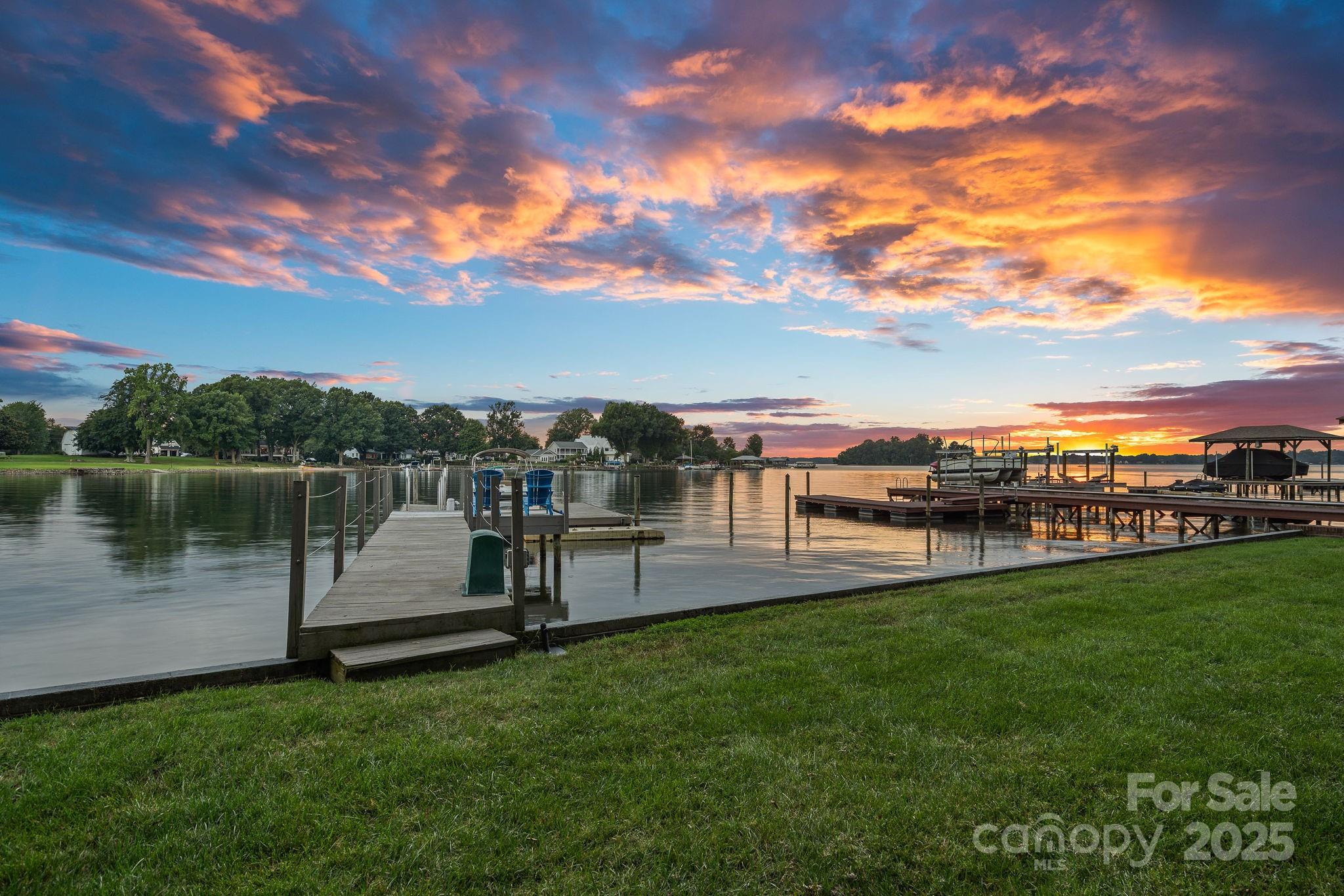 Welcome to your lakeside escape, where every day ends with a sunset! Enjoy long range, main channel Lake Norman views from this eclectic lake house filled with warmth and charm. Perfectly set on a beautifully landscaped, flat lot with a large grassy yard and mature trees. Thoughtfully updated throughout, the home offers the comfort of dual primary suites, one on each level making it easy to host family and friends. The cozy sunroom is the heart of the home, where you’ll want to linger with morning coffee or curl up in the evenings while the lake glimmers outside your window. Step outside and life on the water is yours to enjoy, with a private dock and boat lift ready for endless lake days. Whether it’s boating, entertaining, or simply relaxing under the trees, this property was designed to make every moment feel special. This is more than a lake house—it’s a place where memories are made, laughter is shared, and sunsets are never missed. Newer roof & gutters (2022), HVAC (2018 & 2022).