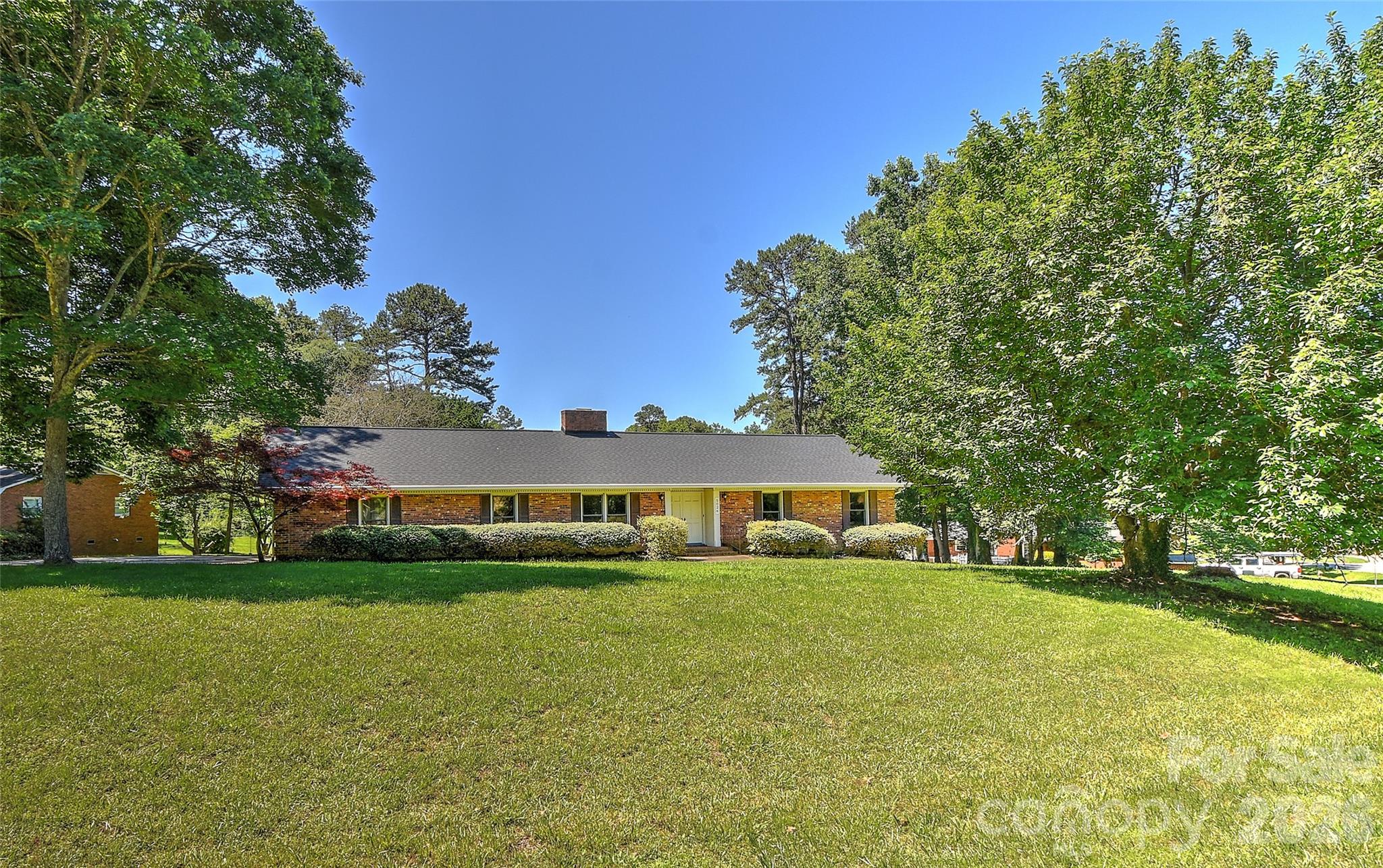 Full brick ranch tucked into a 1/2 acre quiet cul-de-sac! Updates include brand new wood look laminate flooring, new roof 2025, new tiled primary bath shower 2022, new water heater and furnace 2021, connected to city water 2021 and new A/C 2020. Double doors open to the welcoming foyer and spacious living room. Crown & chair rail moldings accent the adjoining dining room. The kitchen features freshly painted cabinets & stainless steel appliances. Large family room boasts an eye-catching masonry fireplace flanked by display shelves and a built-in cabinet. Double doors with screens open to the deck for outdoor entertaining. The primary bedroom includes a tiled bath with double vanity, walk-in closet and updated tiled shower with frameless glass. Two additional bedrooms both have lighted ceiling fans and 2 double closets. The carport has a large laundry room with sink & overhead cabinets as well as a storage room. Great location just 1 mile from Downtown Mint Hill and minutes to I-485 access! New Ezell Farms Park is just across the street from the neighborhood and features a playground, splash pad, pickelball and basketball courts and walking trails!