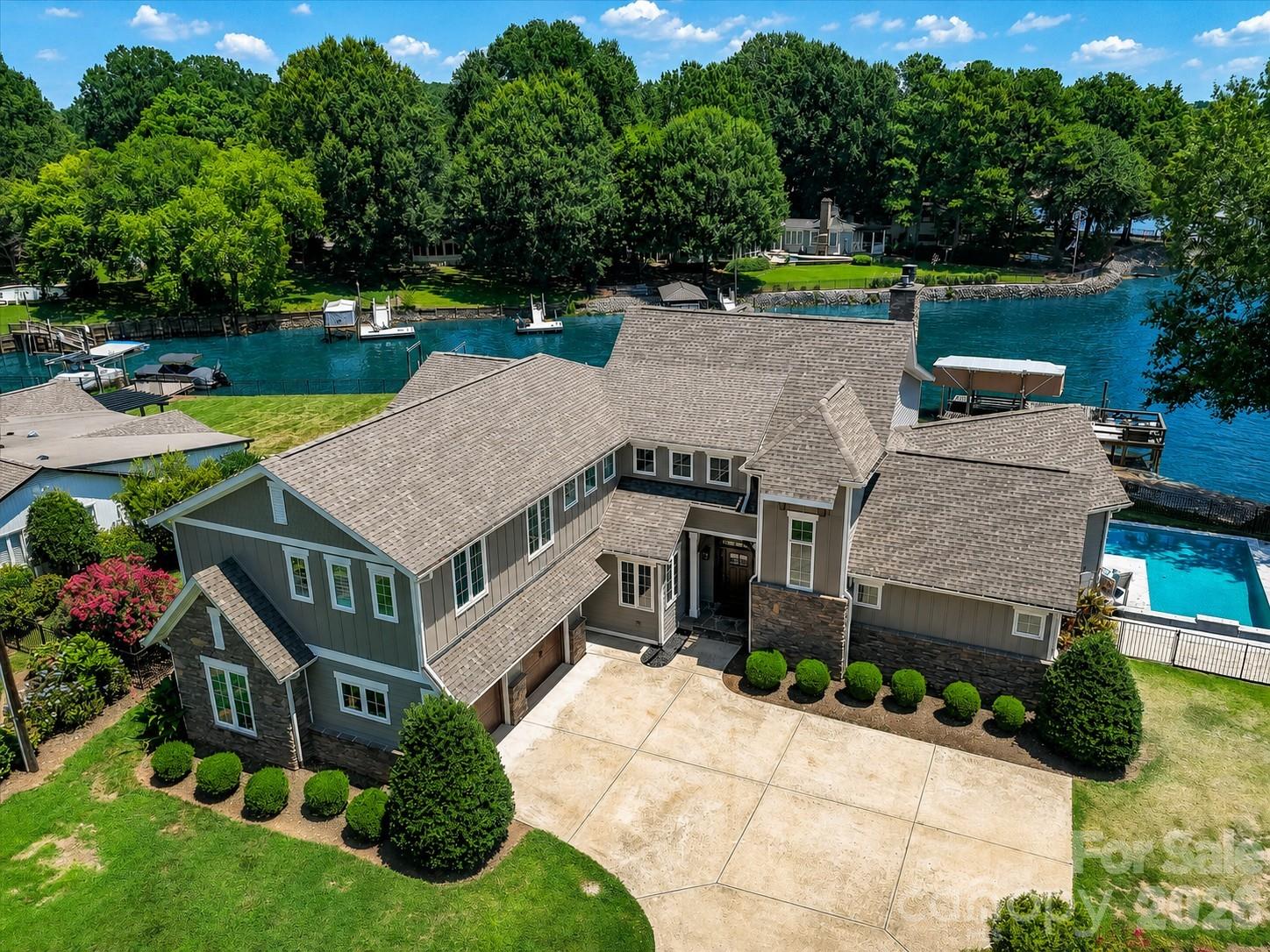 Experience refined waterfront living on Lake Norman in the sought-after Point Largo community, where long-range water views and exceptional amenities create a truly elevated lifestyle. Built in 2017 by Signature Homes, this impressive opulent residence offers over 5,200 square feet of thoughtfully designed living space with five bedrooms and five full baths. The light-filled open floor plan showcases expansive lake views from the main living areas, seamlessly connecting the chef’s kitchen—complete with a large island, induction cooktop, walk-in pantry, breakfast bar, and built-in appliances—to the inviting keeping room with fireplace and a lakeside family room with stone fireplace as well. Sliding glass doors extend the living space outdoors to a resort-style setting featuring a saltwater pool, covered patio, and fenced backyard, all overlooking the serene waters of Lake Norman. The main-level primary suite serves as a tranquil retreat with stunning lake views, a spacious walk-in closet, and a spa-inspired bath with dual vanities and an oversized walk-in shower. Additional living spaces include a media room, game room with dry bar, and flexible bonus areas ideal for recreation, guests, or working from home. Completing this exceptional property is a private dock with boat slip, boat lift, floating dock, and personal watercraft lift, along with access to the community’s private beach—offering the ultimate opportunity to enjoy boating, swimming, and lakeside relaxation. Ideally located in Cornelius near premier shopping, dining, and everyday conveniences, this remarkable home blends luxury, comfort, and breathtaking waterfront scenery.