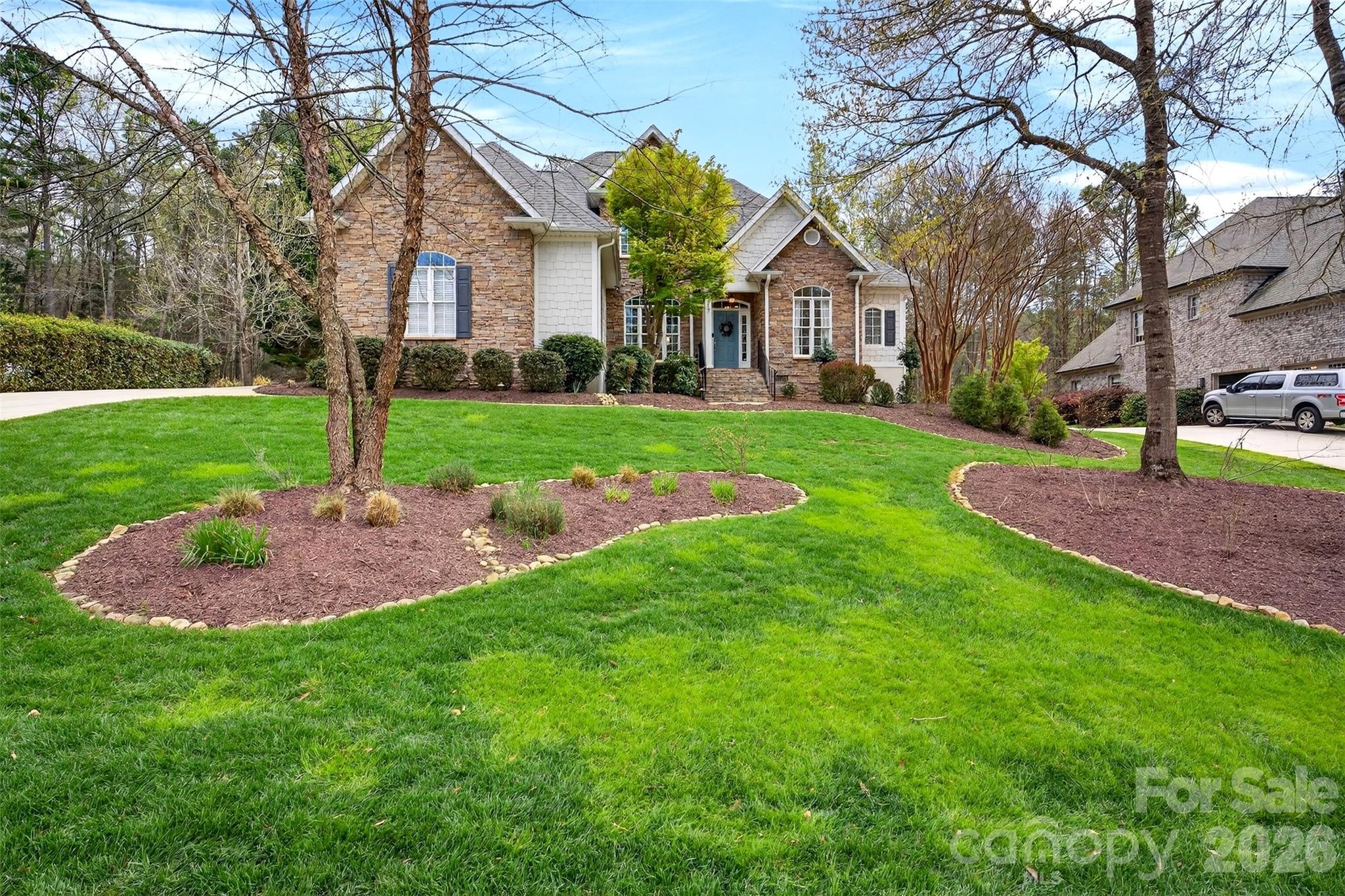 SELLER MOTIVATED TO SELL QUICKLY!  Located in a private golf, tennis, pickle ball community, this grand home combines timeless architectural detail with modern, eco-friendly efficiency. From the striking stone entry and shaker shingle Hardie Plank siding, every inch of this home has been curated for luxury and comfort. Step inside to a sun-drenched living room where a wall of windows offers panoramic views of the professionally landscaped backyard. The main level is designed for both entertaining and comfortable living. The Formal Dining features exquisite wainscoting for a touch of classic elegance. A Private Office, tucked behind French doors, boasts soaring cathedral ceilings. The Cozy Den, the heart of the home, is centered around a floor-to-ceiling stone fireplace and has cathedral ceilings and views of the back yard. A built-in coffee and beverage bar with a wine fridge makes this the ultimate relaxation spot. The centrally located kitchen is a masterpiece of function and style, featuring premium appliances, A Bosch 5-burner range, Bosch wall oven and warming drawer, plus a Fisher & Paykel dual-drawer dishwasher. The Kitchen has designer finishes with rich warm wood cabinetry, granite countertops, and fashionable lighting. In addition, A large Walk-in Pantry with a dedicated "mudroom" zone featuring cubbies for organized storage and the Laundry Room is a high-end workspace with quartz countertops and a utility sink. The Primary Bedroom, located on the main floor, features a cozy fireplace, "his and her" walk-in closets, and direct access to the back porch. The spa-like primary bath includes warm blonde wood soft-close cabinetry and granite surfaces. The Upper Level has three additional oversized bedrooms, including one with a private en-suite bath. A massive walk-in attic provides effortless storage for seasonal items. Enjoy the outdoors from your screened sunporch or the beautiful landscaped backyard. A newer roof (2020) equipped with solar panels that will be paid off at closing. These panels provide a monthly credit to the owner. A tesla wall charger is installed in the garage and a 240V outlet to charge EV's. Carolina Country offers a 24 hour guarded gate, walking trails and event spaces set within a neighborhood of rolling hills and lakes. Call today for a personal showing.