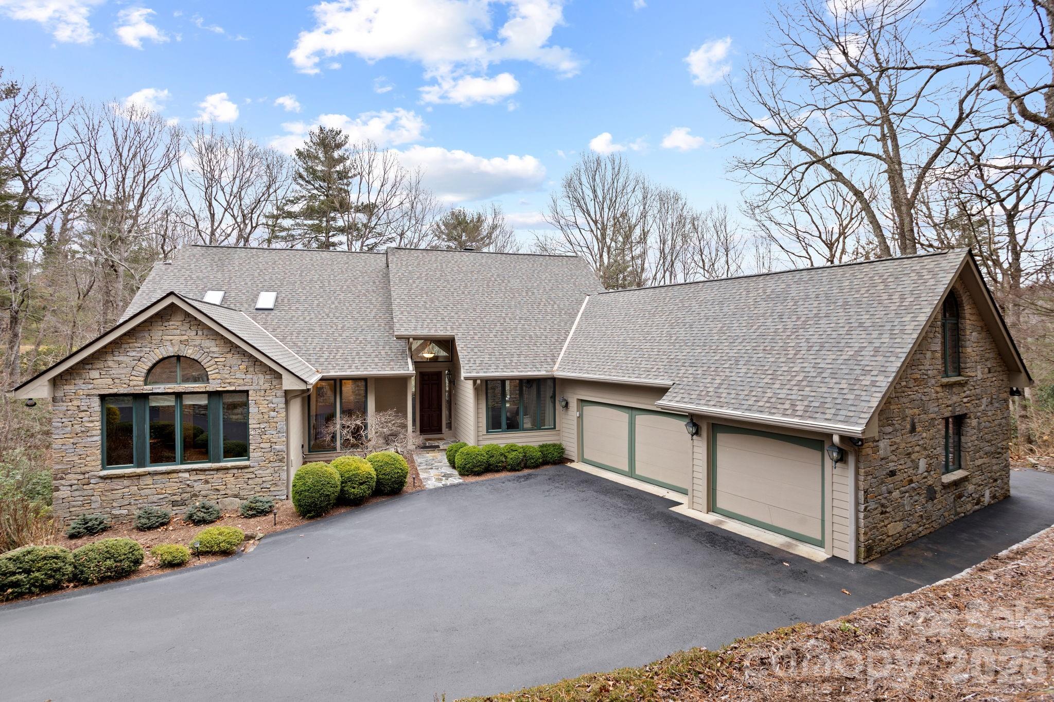 Exceptional luxury home situated on 2 private acres overlooking the signature 17th hole in prestigious Kenmure, a gated golf course community. This truly unique property is surrounded by mountain streams and cascading waterfalls that flow throughout the grounds, creating a peaceful and private mountain retreat. The main level features an outstanding great room with soaring vaulted ceilings and tongue-and-groove willow wood ceiling, complemented by an impressive floor-to-ceiling wall of windows showcasing the natural setting. A stunning stone gas fireplace anchors the space and opens seamlessly to a den/TV room with custom built-ins—ideal for entertaining and gathering with guests. The expansive gourmet kitchen is designed for the serious chef and entertainer, offering high-end stainless steel appliances, including a Dacor six-burner gas range with double ovens and exhaust hood. The sink area is flanked by two Fisher-Paykel dishwashers, along with an Sub-Zero refrigerator/freezer, two islands (one with breakfast bar), granite countertops, and an abundance of cabinetry with unique pull-outs. A breakfast bar and additional casual breakfast space further enhance the kitchen’s functionality. The dining room features a wall of windows, bringing the outdoors in. The expansive primary suite is a private retreat and offers a sitting area, walk-in closet with laundry chute, washer/dryer hook-up plus add’l closet and a private sunroom accessed by 2 glass French doors overlooking the serene landscape and waterfalls. The spa-like bath includes a walk-in tile shower, Jacuzzi tub, double vanity, large linen closet and vaulted ceilings. Also on the main level is a beautiful study with large picture windows, palladium accents, walk-in closet, vaulted ceiling and tongue-and-groove willow wood ceiling. A gorgeous powder room with vessel sink and custom vanity adds elegance, while the mudroom off the garage includes an additional half bath. The lower level is perfect for entertaining, featuring a large family room/recreation area with bar, sink, beverage refrigerator, and seating. A dramatic floor-to-ceiling stone wood-burning fireplace is enhanced by a convenient dumbwaiter for transporting firewood. Two guest bedrooms and two en-suite guest baths complete this level. The laundry room offers cabinetry, sink, and a convenient laundry chute from the primary suite. Additional features include a dog-washing station and planting/garden area in mudroom and a heated and cooled workshop. Outdoor living is truly exceptional with multiple levels of decking, tranquil waterfalls, flowing streams, and private walking trails throughout the property with footbridge to the golf course—all while overlooking the 17th signature hole of the golf course. Additional highlights include a three-car garage with rear golf cart access and its own driveway, new roof, whole-house generator, two HVAC systems and two water heaters. Ideally located just minutes from the entry gate and Kenmure’s outstanding amenities. A rare opportunity to own a luxury mountain home offering privacy, views, and an unparalleled natural setting.