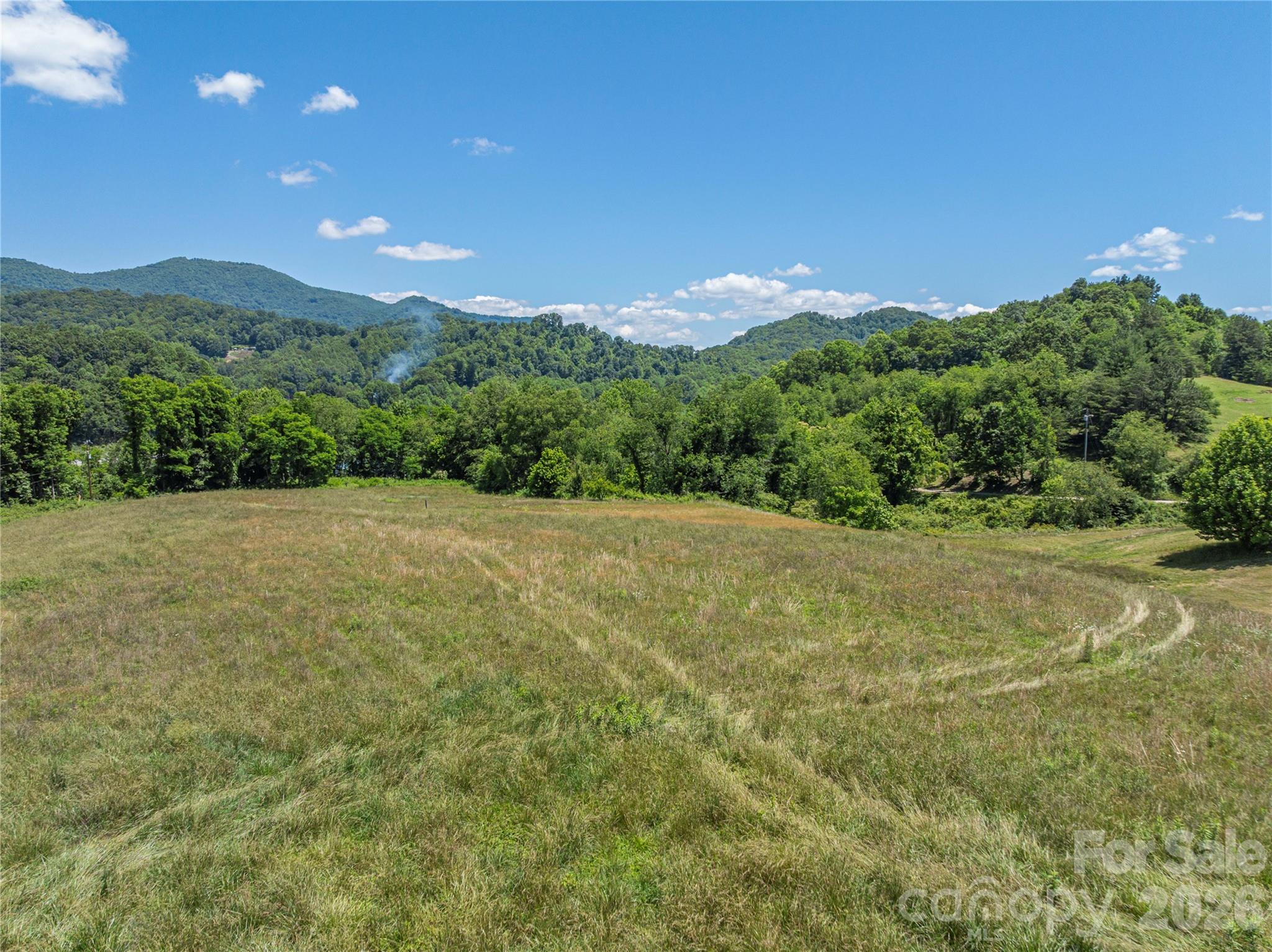 Prime Development Opportunity in Waynesville Exceptional opportunity to acquire nearly 6 acres of highly visible and accessible property along the Great Smoky Mountain Expressway, just minutes from downtown Waynesville. Offering breathtaking long-range mountain views in every direction, this unique property combines location, utility, and redevelopment potential in one remarkable package. The property features a large historic apple processing warehouse, an additional garage/shop building, and expansive usable acreage with gently rolling topography that lends itself to a wide variety of commercial, mixed-use, residential, or investment-oriented projects subject to zoning. The land lays exceptionally well, providing flexibility for future development while maximizing the stunning mountain vistas that surround the site. With direct exposure to one of the area’s primary transportation corridors, the property benefits from excellent visibility and convenient access, making it an ideal candidate for businesses seeking a prominent location or developers looking to capitalize on Waynesville’s continued growth. The historic warehouse structure offers substantial square footage and character, presenting an opportunity for restoration, adaptive reuse, storage, barn, event space, artisan production, or other creative redevelopment concepts. While the building requires renovation, its scale and history provide a unique foundation for a visionary project. Infrastructure advantages include an existing well, available public water connection, and natural gas access, adding significant value and development flexibility. Whether you’re seeking a commercial headquarters, residential development site, mixed-use project, mountain retreat, or investment property, this versatile tract offers endless possibilities in one of Western North Carolina’s most desirable locations. Endless possibilities, unmatched views, and a strategic location make this a truly unique Western North Carolina offering.