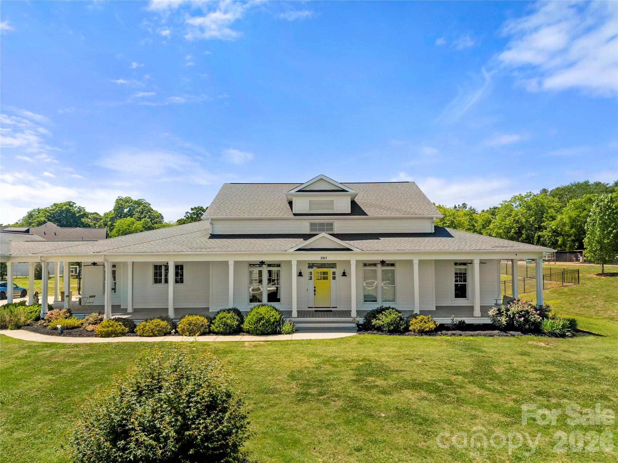 Welcome to your ultimate private oasis in Monroe, NC! Nestled on 5 sprawling acres of pristine land, this spectacular 4,700-square-foot custom 1.5-story home effortlessly blends modern luxury with timeless farmhouse charm, immediately greeting you with a grand wrap-around front porch and a striking yellow front door. Designed for effortless living, the airy, sun-drenched open floor plan flows seamlessly into a chef's dream kitchen featuring a massive central island and dual side-by-side refrigerators. Five of the six massive bedrooms are conveniently located on the main floor, including a luxurious primary retreat with a spa-like ensuite bath. Multiple versatile flex spaces throughout the home serve perfectly as private home offices or distinct sitting areas, complemented by oversized closets and abundant storage. For ultimate convenience, the home boasts a dedicated main laundry room plus an additional stackable laundry unit nestled near the secondary bedrooms. Outside, you can relax on the breezy screened porch overlooking your private, sparkling in-ground pool and vast acreage, while a detached three-car garage provides a massive storage space above. This rare acreage property offers unparalleled peace, privacy, and upscale amenities, making it a custom masterpiece you must experience in person.