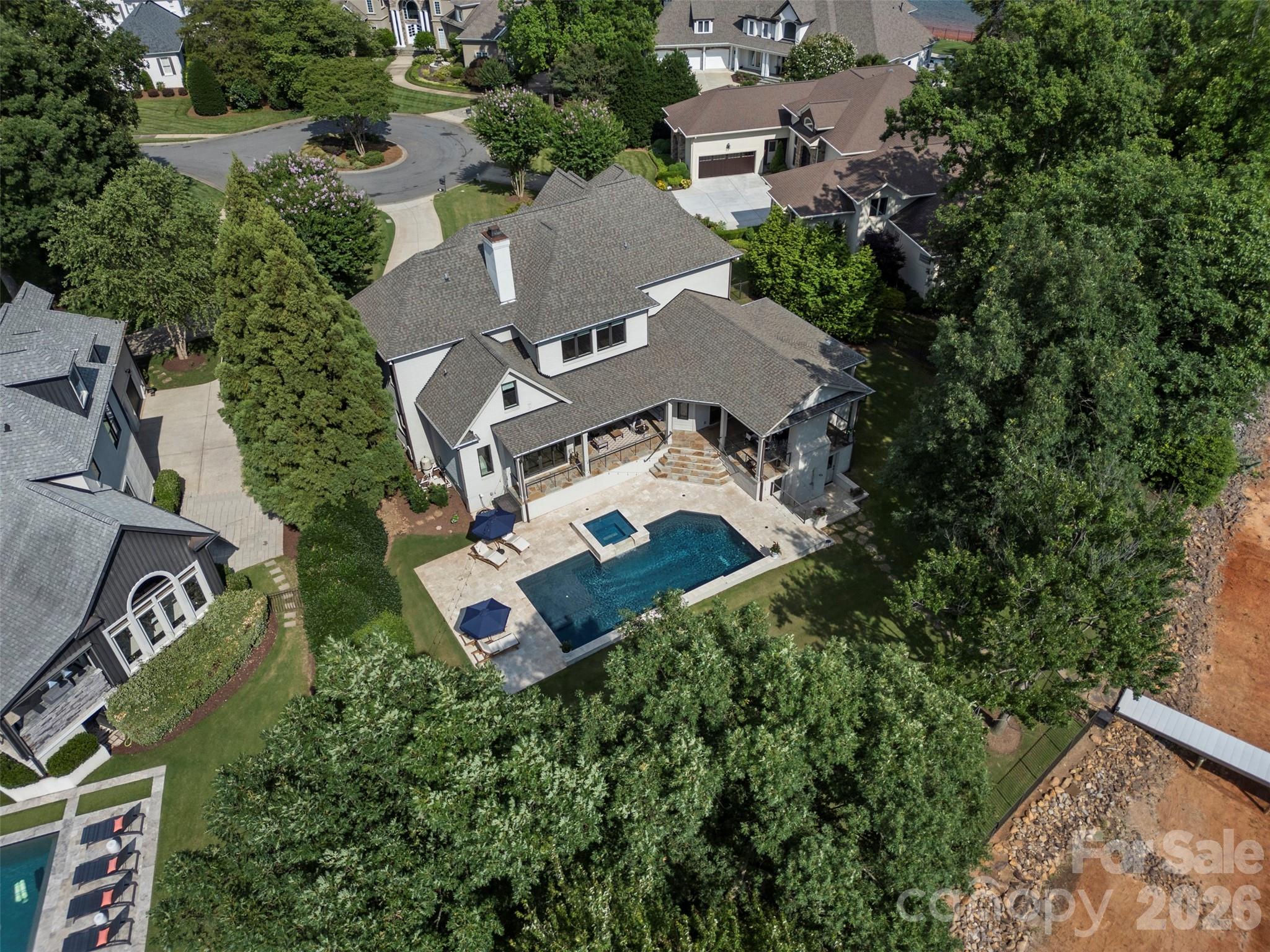 Waterfront luxury in this exceptional all-brick estate nestled within the prestigious Peninsula community. Showcasing quiet cove views of Lake Norman, this updated residence seamlessly blends elegance with modern luxury.  Outdoor living is unrivaled, featuring covered wraparound loggias, an outdoor kitchen, a stone fireplace, heated pool and spa, pool bath, outdoor shower, private dock, and a sprawling fenced lakeside lawn ideal for entertaining and recreation.  Thoughtfully designed main level offers an expansive open floor plan highlighted by walls of sliding glass doors that capture stunning water views and create effortless indoor-outdoor living. At the heart of the home is a fully renovated chef's kitchen featuring quartzite island, custom cabinetry, dual dishwashers, premium appliances, and a beautifully appointed scullery for additional preparation and storage. The luxurious primary suite serves as a private retreat with a spa-inspired bath, custom closet, personal laundry area. Additional main-level spaces include a welcoming great room with fireplace, formal dining room with coffered ceiling, keeping room and breakfast nook with banquette.  Upstairs, three generously sized bedrooms each enjoy beautifully updated en-suite baths with designer wall coverings. A spacious bonus room offers flexibility as a fifth bedroom, media room, or playroom. A dedicated office and full-size laundry room complete the upper level.
Additional highlights include a 3-car epoxy garage enhanced by a professional-grade automotive storage lift, allowing expanded vehicle capacity for car enthusiasts and collectors.  Located just a short stroll from The Peninsula Golf Club and minutes from premier dining, shopping, and conveniences, this remarkable waterfront residence offers the very best of Lake Norman luxury living.