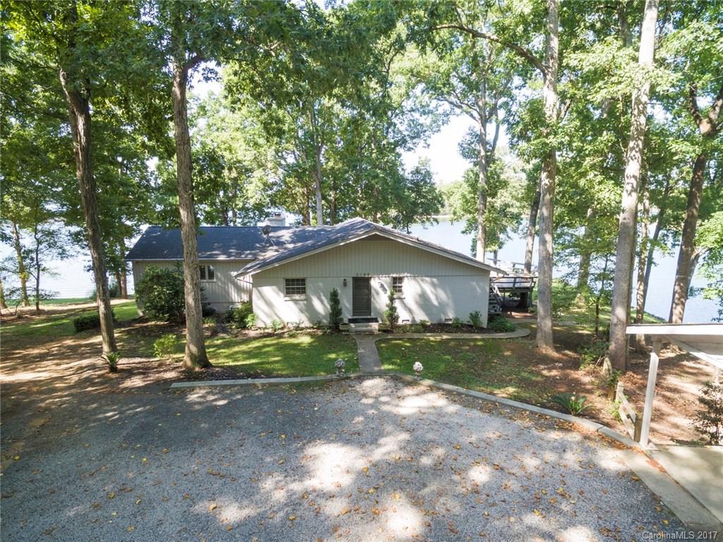 THIS UNIQUE RANCH-STYLE LAKE FRONT HOME HAS LOADS OF CHARACTER!  IT CHARMS AND WELCOMES FROM THE WOOD FLOORS, OPEN FLOOR PLAN AND VAULTED GR CEILING TO 180 DEGREE VIEWS FROM THE 1000+ SQ. FT. WRAP-AROUND DECK.  THE 5 ACRE PROPERTY HAS OVER 500 FT OF FRONTANGE ON LAKE WYLE, A SHELTERED SAND BEACH, DOCK & BOAT-LIFT, AND 3.5+ WOODED ACERS.  NO HOA FEES.  YORK COUNTY TAXES.   FORT  MILL SCHOOLS.  15 MILES TO UP-TOWN CHARLOTTE.  FIREPLACE(S) CONVEY AS IS.