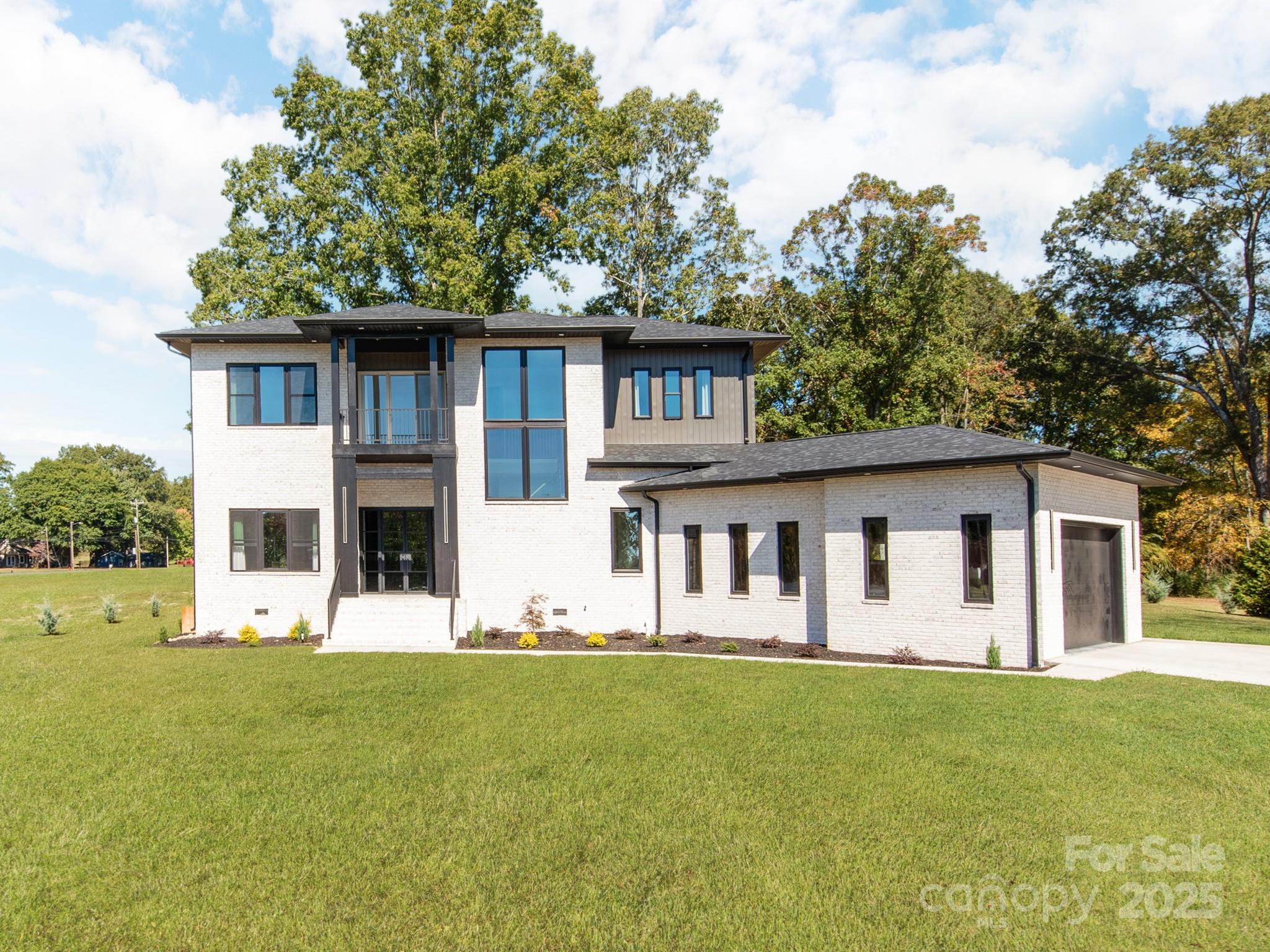 New Price ! New Construction –2025 Build- Contemporary Elegance Meets Modern Functionality. Discover this stunning newly built contemporary brick home, designed with an open-concept floor plan and soaring 12'+ ceilings on the main level. From the moment you arrive, you’ll be captivated by the striking front entrance featuring modern glass double doors and a dramatic open staircase. Inside, expert craftsmanship shines through with custom woodwork, elegant lighting fixtures, and rich hardwood flooring throughout. Abundant windows fill the space with natural light, creating a warm and inviting atmosphere. The chef’s kitchen boasts a sleek L-shaped design with expansive counter space, a large center island, and oversized windows overlooking the outdoors. The kitchen seamlessly flows into the spacious family room and sophisticated dining area—ideal for entertaining or everyday living. Step out from the family room to a generous 360sqft covered rear porch, perfect for relaxing or hosting gatherings. Main-Level Retreat:Luxurious primary suite on the main floor features a spa-inspired bathroom with premium finishes—a true owners retreat. Large laundry/keeping room with a convenient half bath adds functionality to the main level. The oversized 759sqft garage is fully insulated, heated, and cooled—ideal for a workshop, gym, or additional flex space. Upper-Level Comfort:Three large bedrooms each offer large walk-in closets and private en-suite bathrooms. A versatile flex space opens to a 95sqft walk-out porch. 10' ceilings and hardwood floors continue throughout the upper level. Outdoor Features:Set on a large, level lot with a private backyard that backs up to a tree line—offering both beauty and privacy.*some virtually enhanced grass in backyard photo*Don't miss your opportunity to own this exceptional home! Schedule your private showing today.