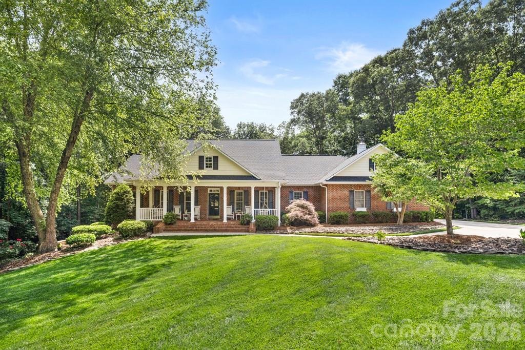Custom brick ranch with fully finished walkout basement nestled on 1.49 private wooded acres in desirable Sigmon Farms. Meticulously maintained and offering exceptional living space, this home showcases quality craftsmanship, custom details, and abundant storage throughout. Rich Brazilian cherry hardwood flooring extends throughout the entire main level, adding warmth and elegance to the home's spacious split-bedroom floor plan. A formal dining room with wainscoting and an elegant living room featuring extensive crown molding, decorative millwork, and large cased openings add character and sophistication to the main living areas. The inviting great room features a trey ceiling, custom built-ins, and a gas log fireplace. The chef's kitchen is designed for both everyday living and entertaining with custom cherry cabinetry, granite countertops, a large furniture-style island with seating, professional-grade gas cooktop, stainless vent hood, double wall ovens, pantry, and abundant storage. Detailed millwork and quality finishes further enhance the home's custom character. The spacious primary suite offers a walk-in closet, garden tub, and separate shower, while two additional bedrooms and a convenient laundry room complete the main level. The fully finished walkout basement expands the living space with beautiful cork flooring, a spacious recreation room featuring a second gas log fireplace, custom lighted display niches, and striking architectural details throughout. Swinging French doors lead to an impressive media room highlighted by a dramatic custom ceiling with accent lighting, creating the perfect space for movie nights, game days, or entertaining guests. A full bath, flex room, and basement garage workshop provide outstanding versatility for hobbies, projects, storage, or home office needs. Outdoor living is equally impressive with a welcoming covered farmer's porch, screened porch, and expansive deck overlooking the private wooded backyard. Enjoy peaceful country living in East Lincoln County while remaining just minutes from shopping, dining, and everyday conveniences in Denver and Lincolnton, with an easy commute to Uptown Charlotte and Charlotte Douglas International Airport.