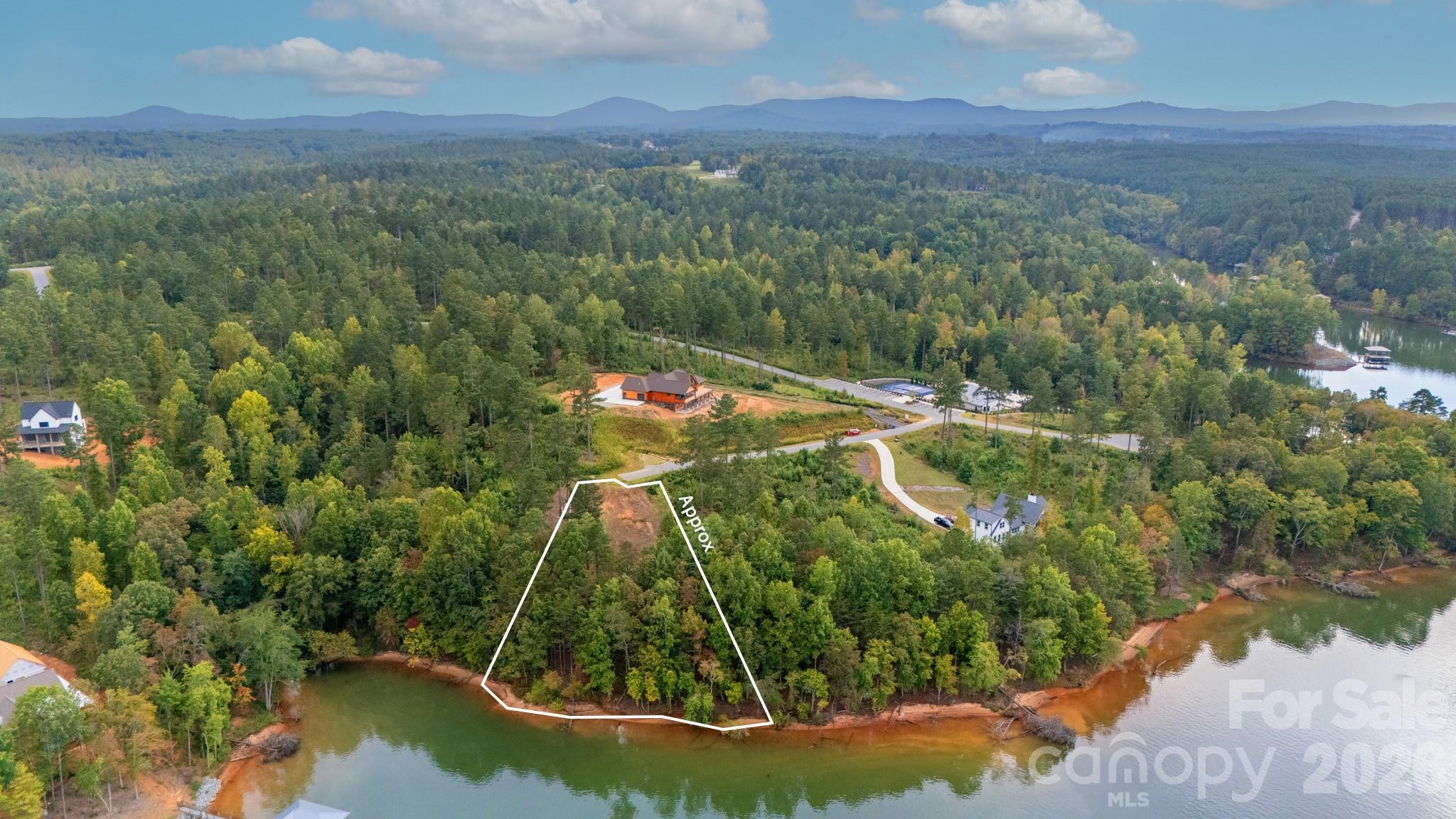 Recently semi-cleared for easy walkable access to the waterfront, this exceptional property boasts breathtaking main channel views with 195 feet of shoreline. Enjoy a sandy beach alongside a spacious, gently sloped area perfect for relaxation. With a brand-new septic permit for a four-bedroom home, this find is truly unique!
Marvel at the stunning Blue Ridge Mountain vistas, where you can witness spectacular sunrises and sunsets. Experience the serenity of a low-traffic lake. HOA Amenities Include: Swimming pool. Pickleball court, Covered patio with outdoor fireplace and kitchen. Lakeside Park featuring a kayak launch Immerse yourself in the beautiful rural countryside, located just minutes from Hickory, NC. Here, you can enjoy a variety of dining options, from casual to fine dining, along with shopping, the Farmers Market, and local festivals. Additionally, Asheville, Charlotte, and Blowing Rock/Boone, NC, are all easily accessible by car.